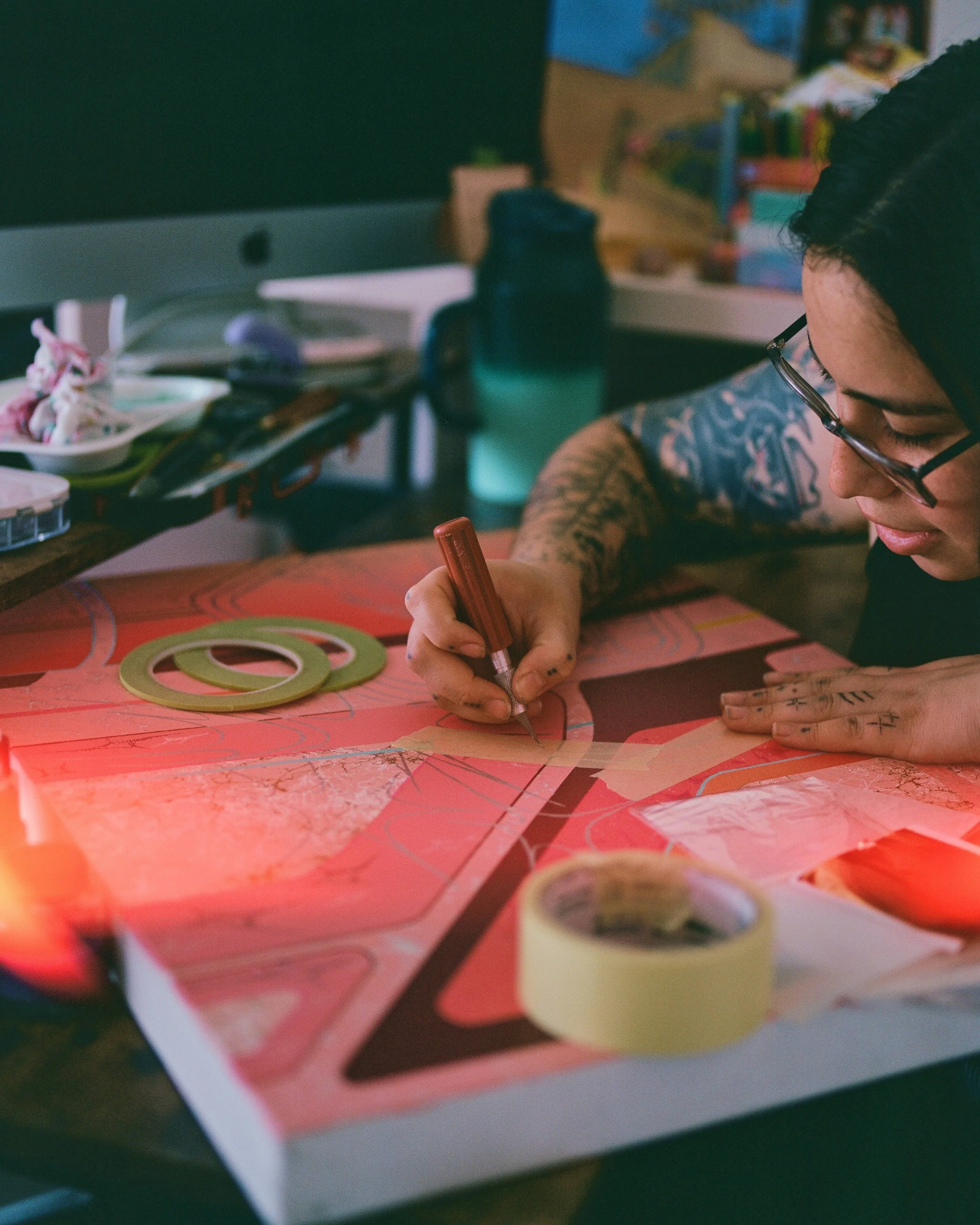 Image of Jacequeline Valenzuela Working on a bright pink canvas in her studio