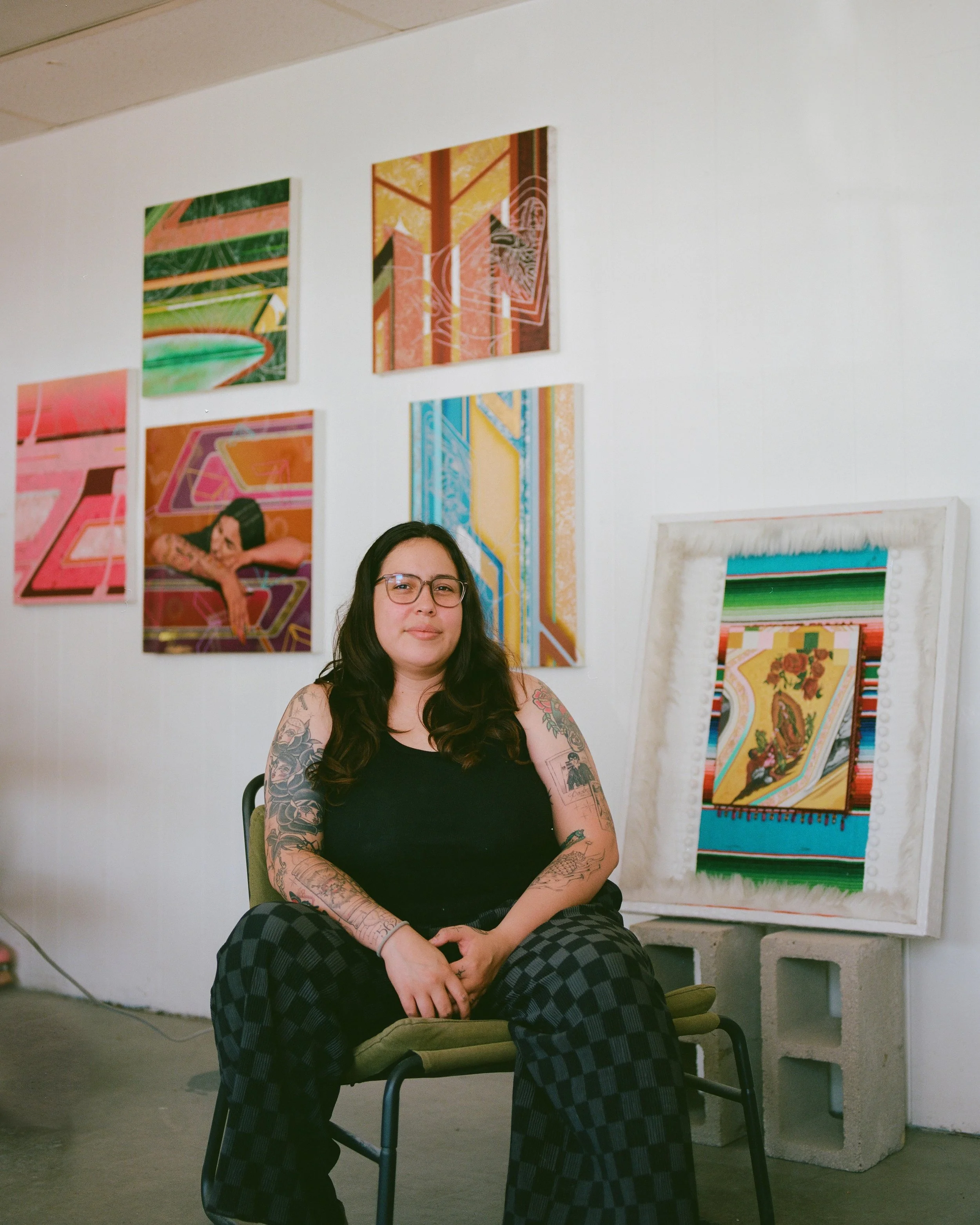 jacueline valenzuela sitting in her studio with canvases in the background
