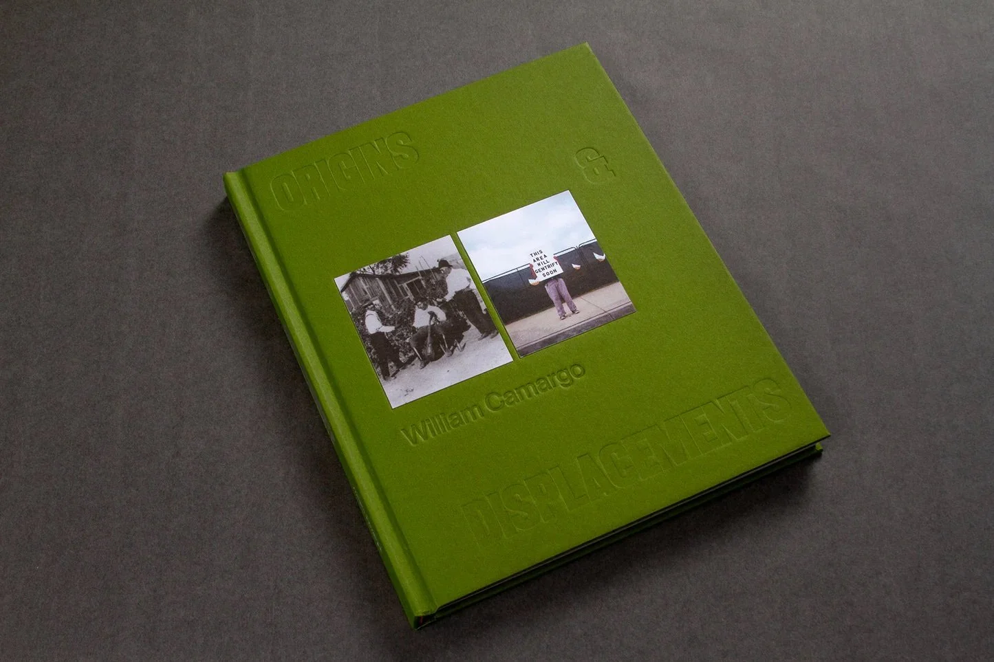 Photo of a green book with two photographs on the cover. "Origins & Displacements" by William Camargo