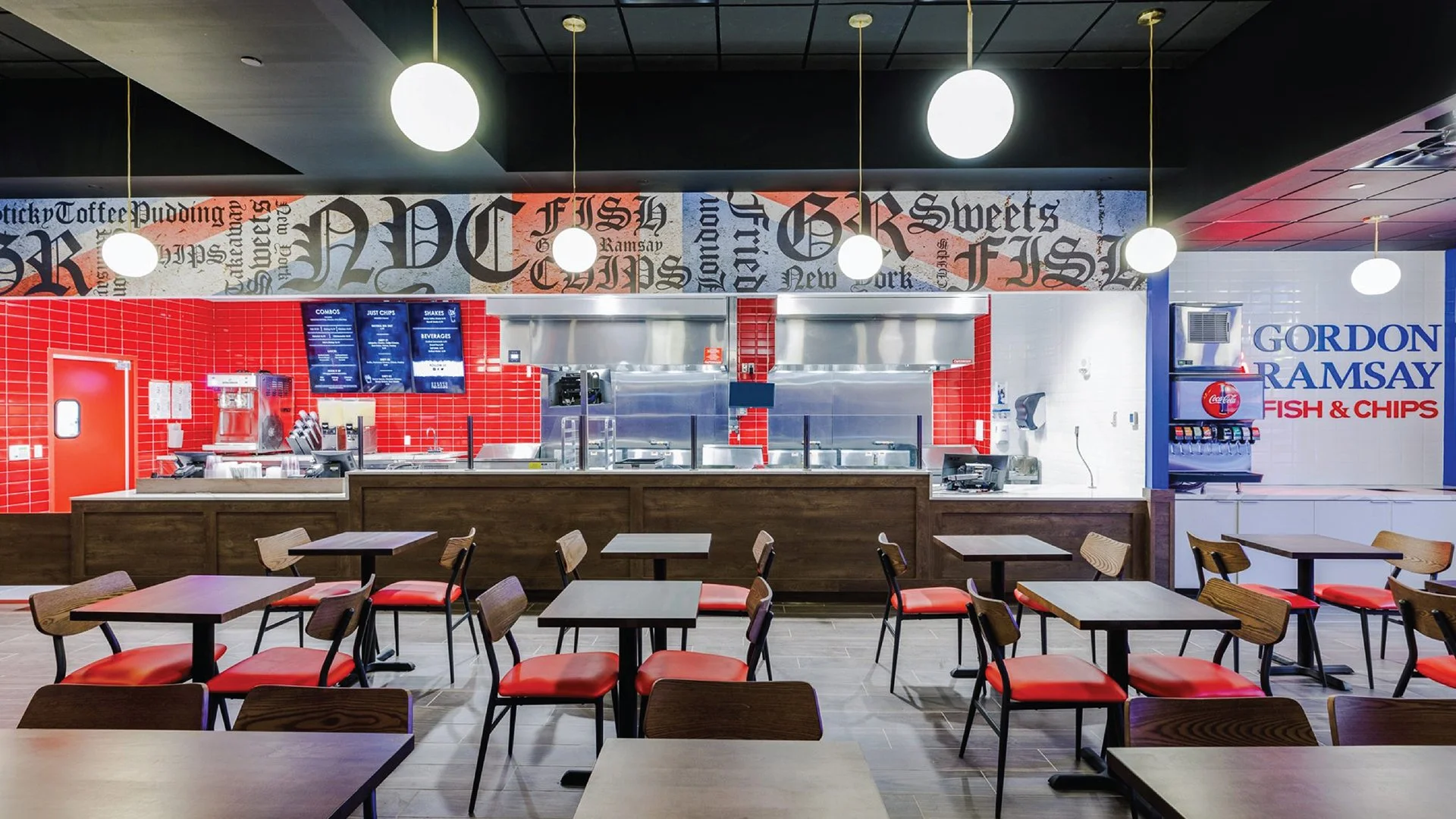 Interior of a casual restaurant with empty tables and red chairs, a counter with a digital menu, red tiled wall, and a soda fountain on the side wall.