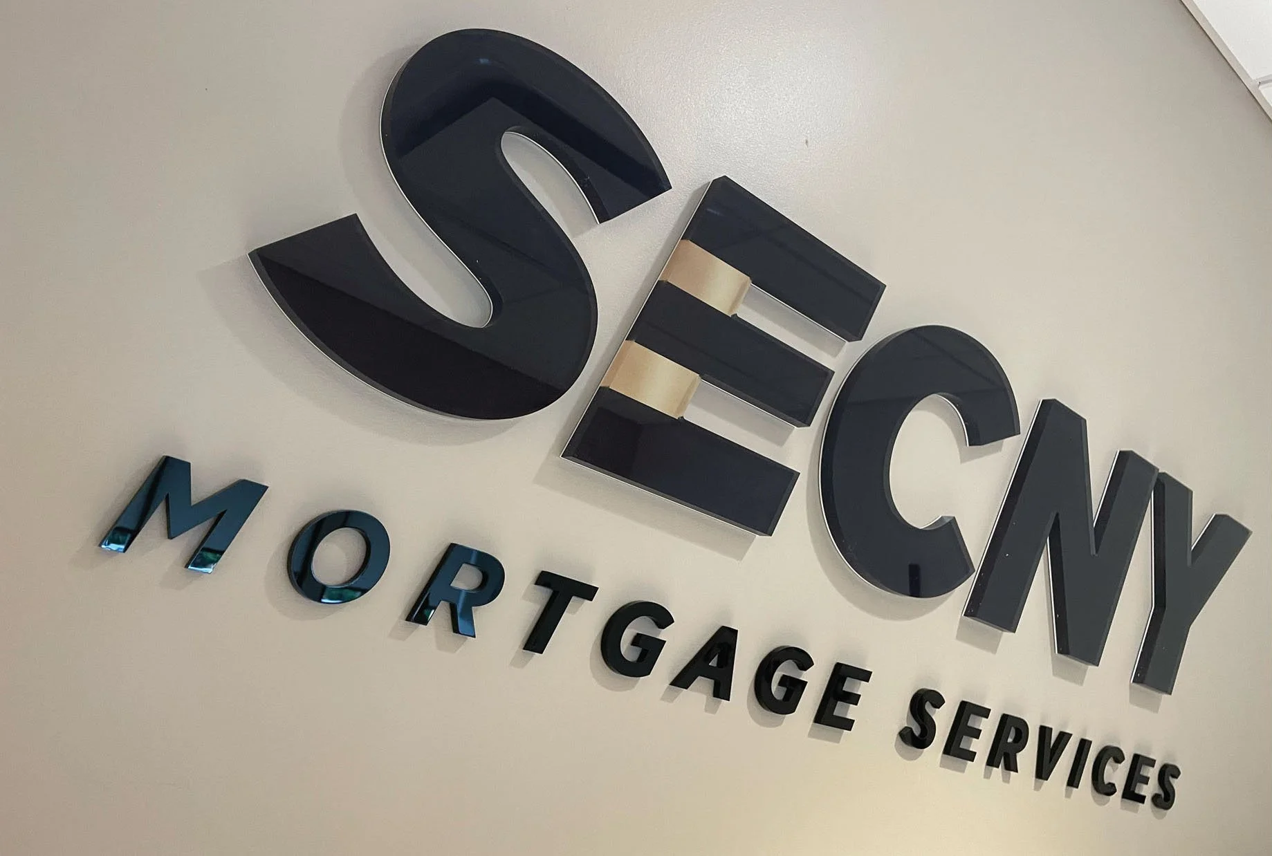 CINSYR | Creative design agency Syracuse, New York | SECNY mortgage services brand identity close in of acrylic SECNY mortgage sign on the wall in the office