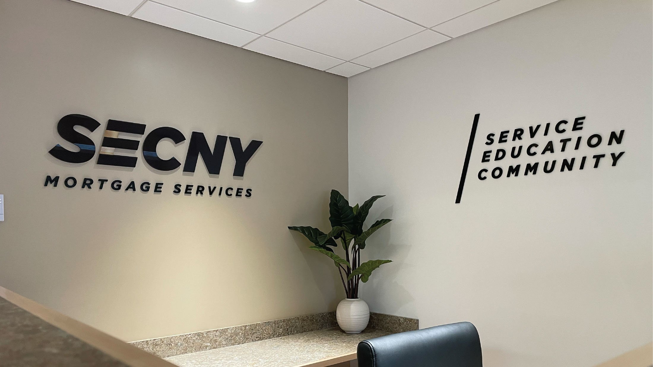 CINSYR | Creative design agency Syracuse, New York | SECNY mortgage services brand identity SECNY mortgage services and Service education and community tagline signs on adjacent walls