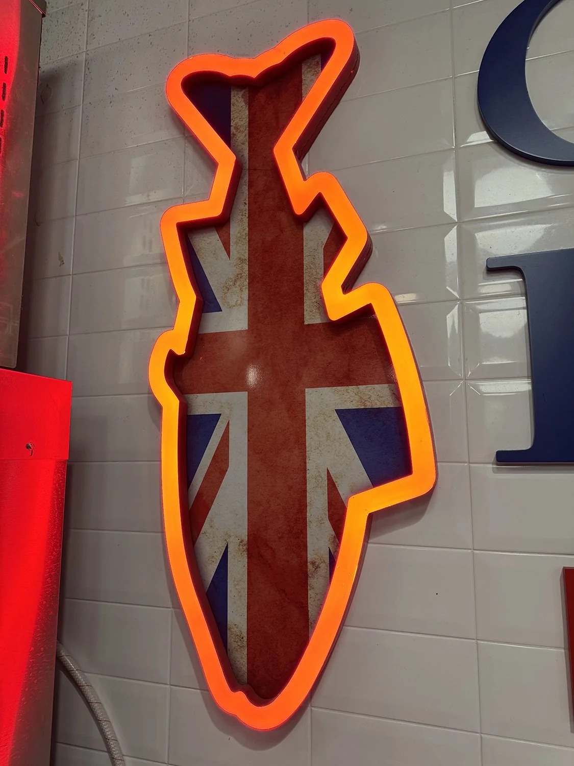 Neon sign in the shape of a stylized motorcycle with the Union Jack flag design in the background.