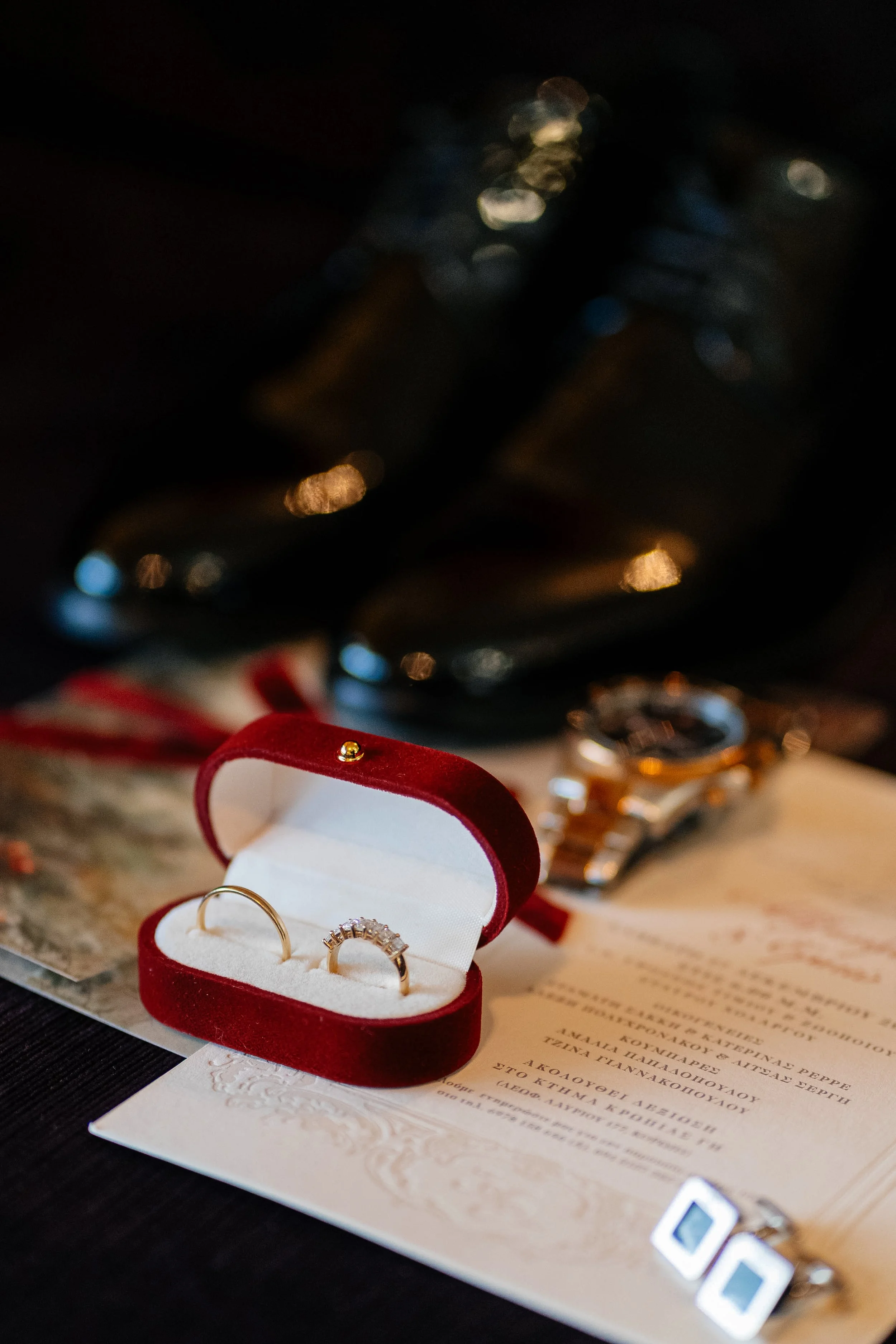 Close-up of a jewelry display with rings in a red velvet box and various jewelry accessories, with a dark background and bokeh lights.