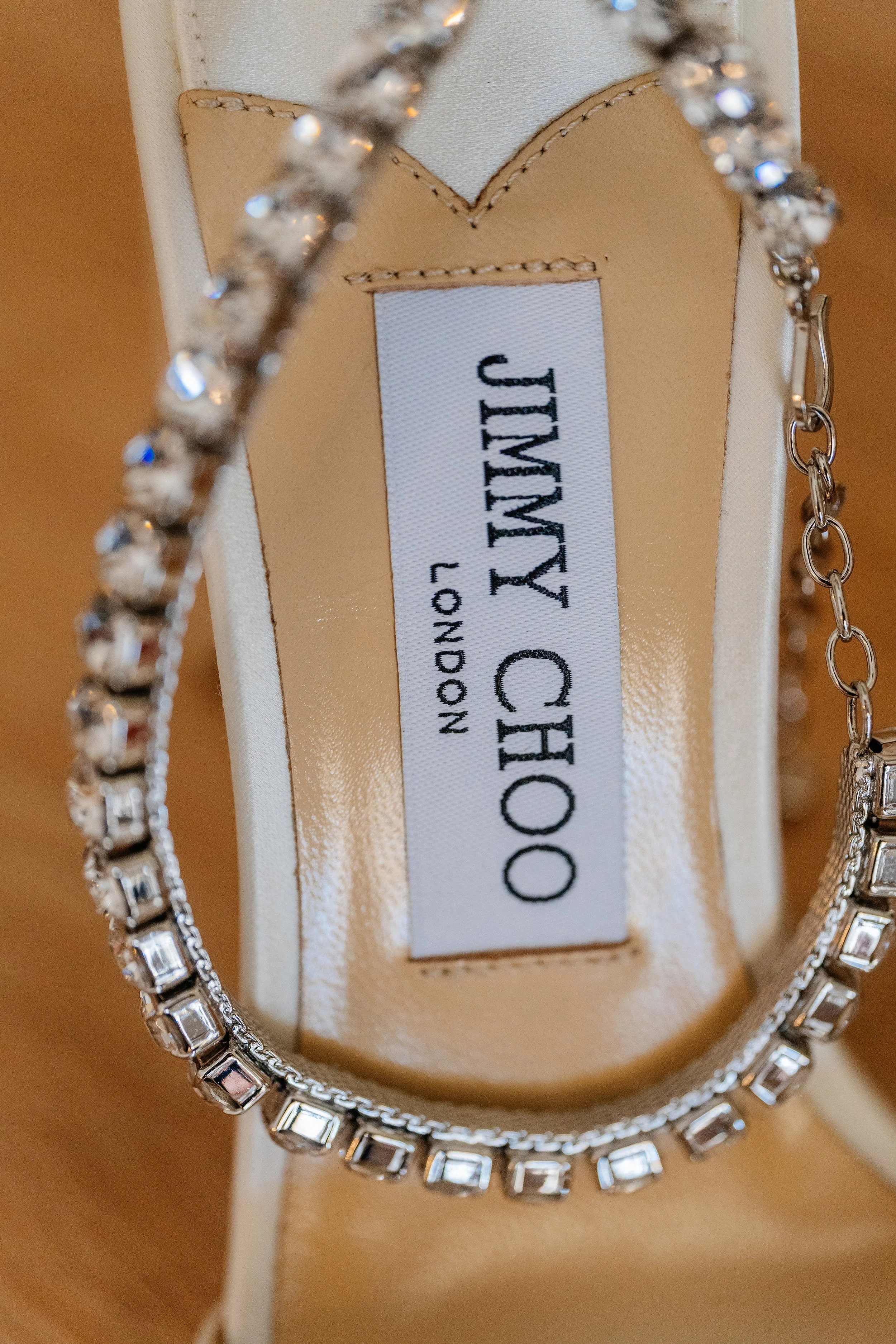 Close-up of a jewelry box with a necklace, possibly diamond or cubic zirconia, and a pair of matching earrings, with a label inside the box reading 'JIMMY CHOO'.