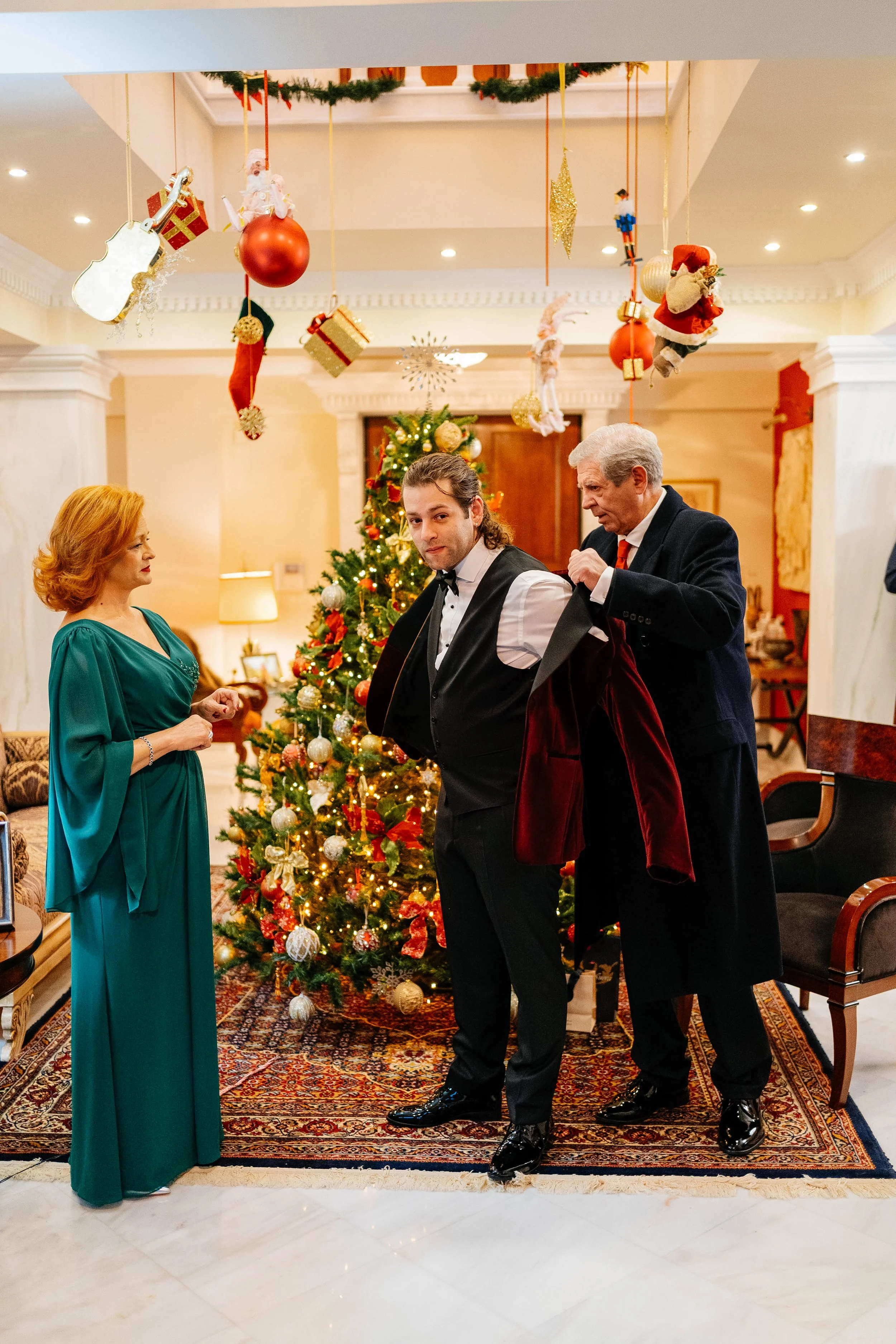 People celebrating Christmas indoors with a decorated Christmas tree and hanging holiday ornaments.