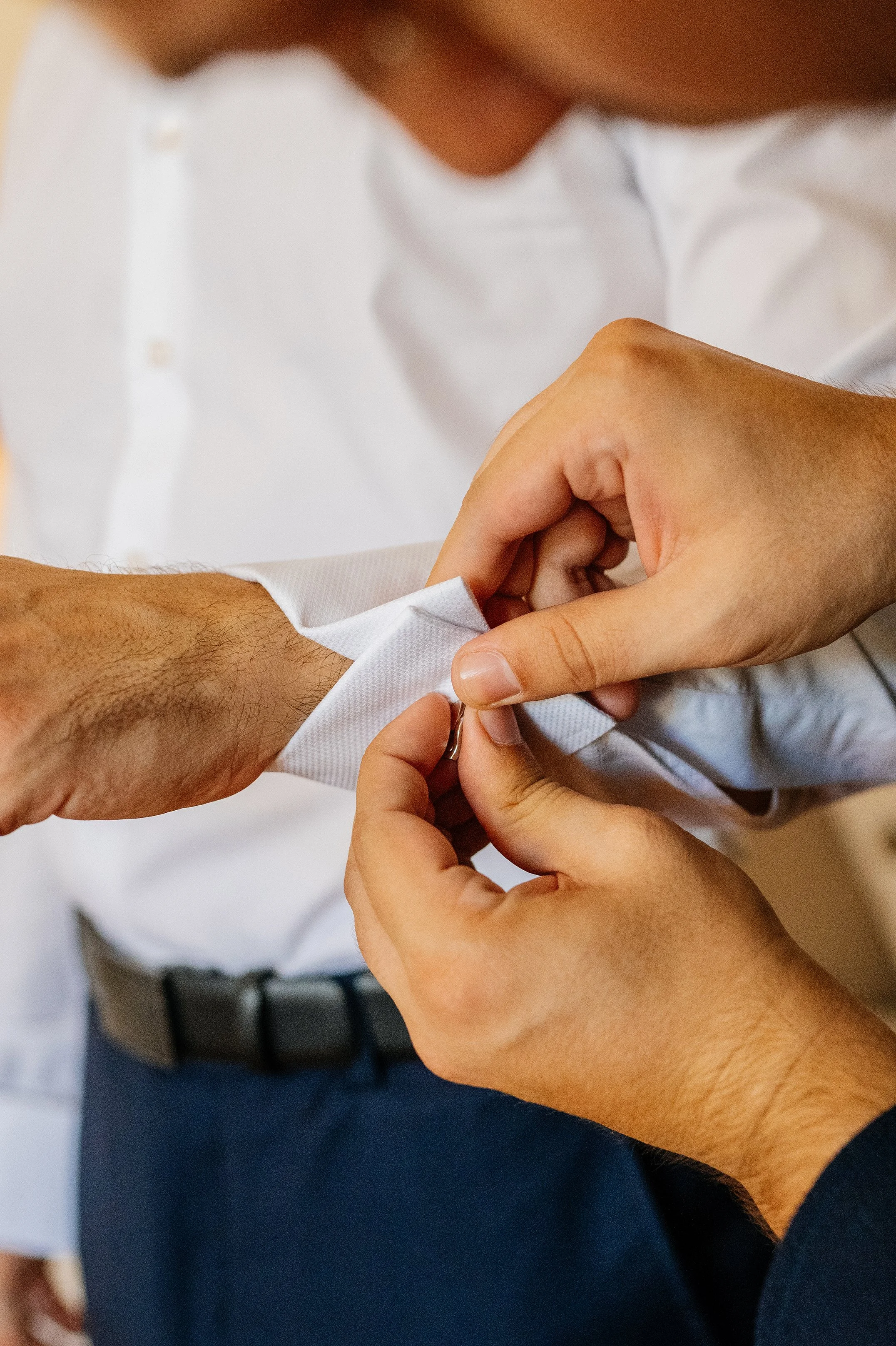 A person in a white shirt is getting a vaccination shot in their upper arm from a healthcare worker. The healthcare worker's hands are visible, handling a syringe.