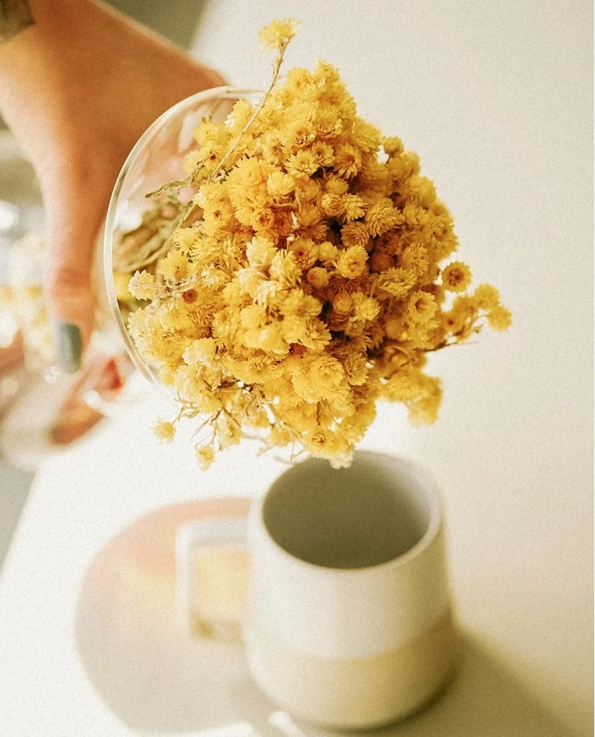 hand holding yellow flowers, white mug