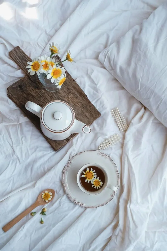 tea and yellow flowers on white bedding