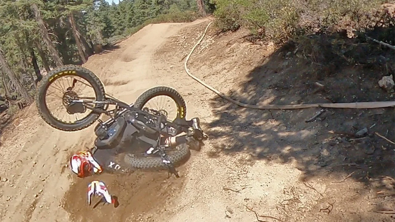 Aaron Baker's adaptive mountain bike crash scene on a dirt trail with a fallen bicycle and helmet.