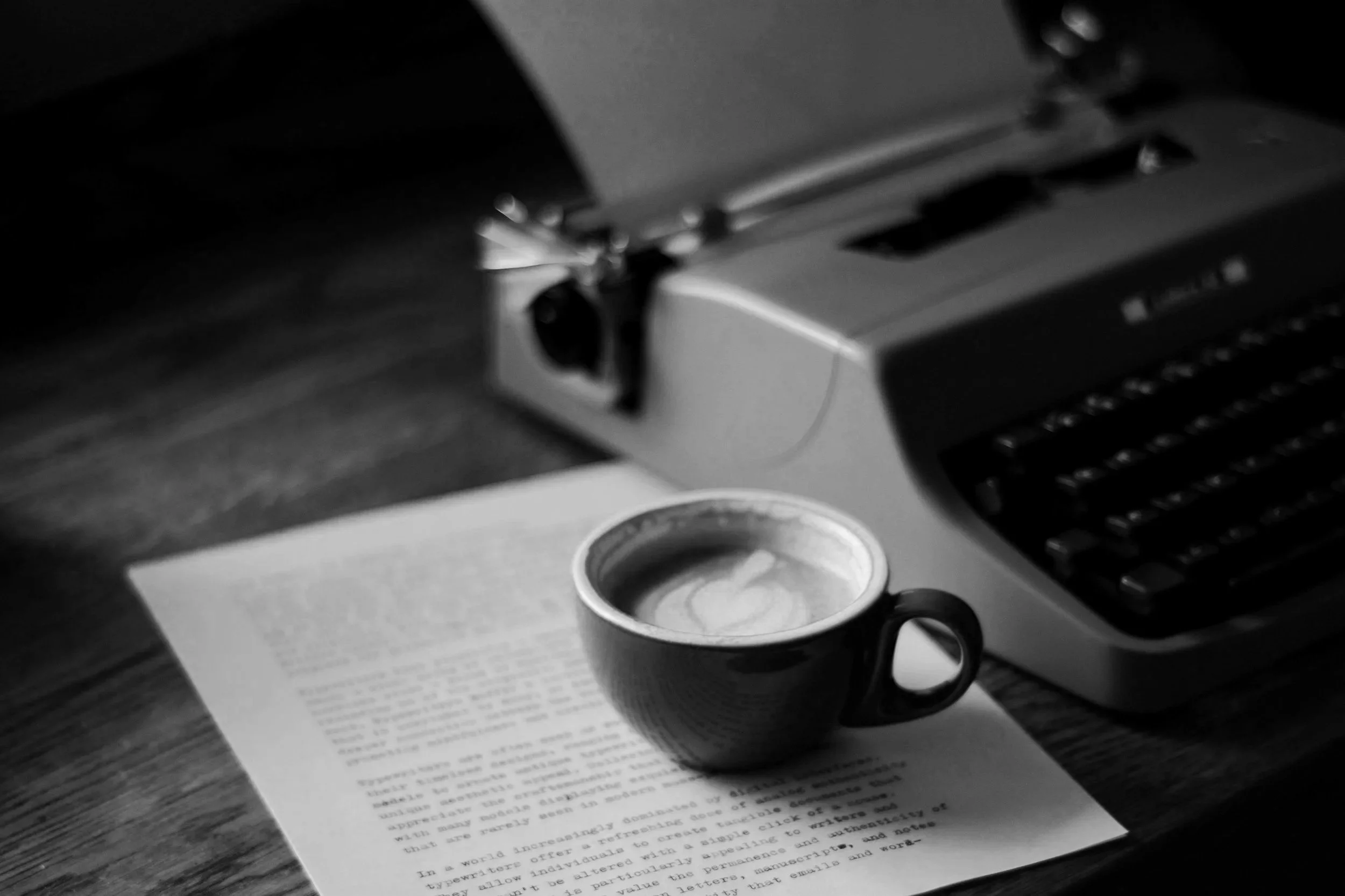 Black and white photo showing a coffee cup, notes and a typewriter.