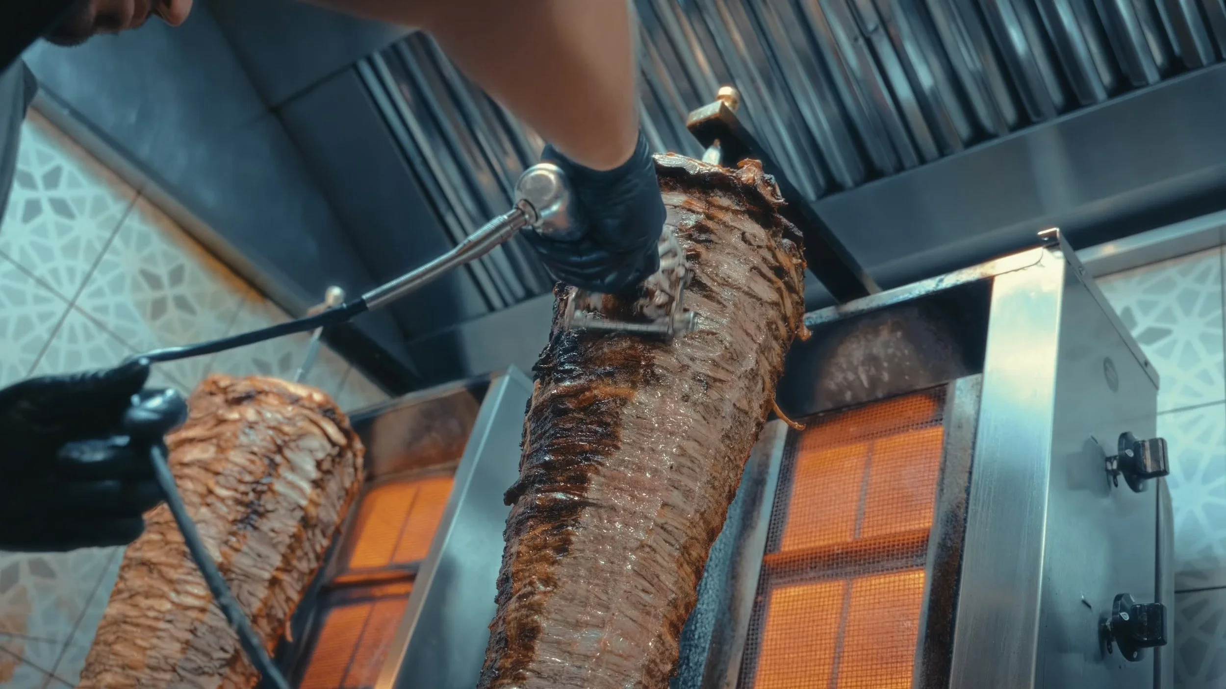 Crowd of people waiting in line at a conference or expo, with some tables and banners along the wall.