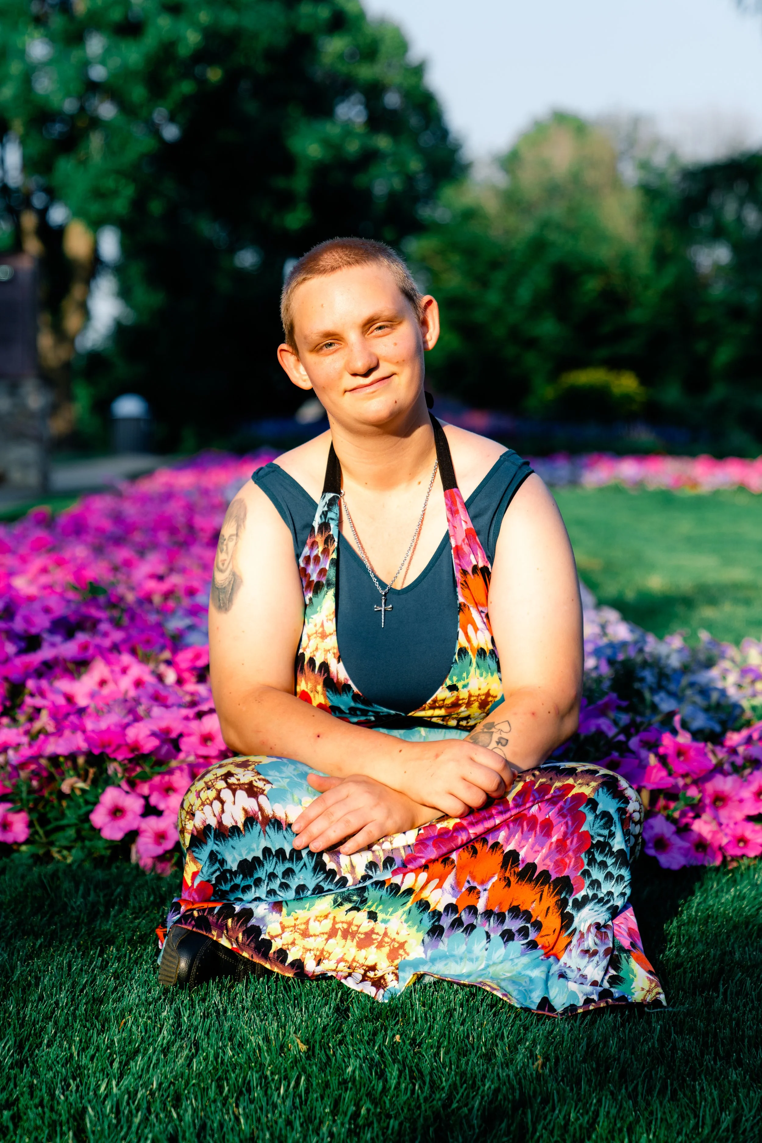The sun shines on Robin as they sit in front of flowers.