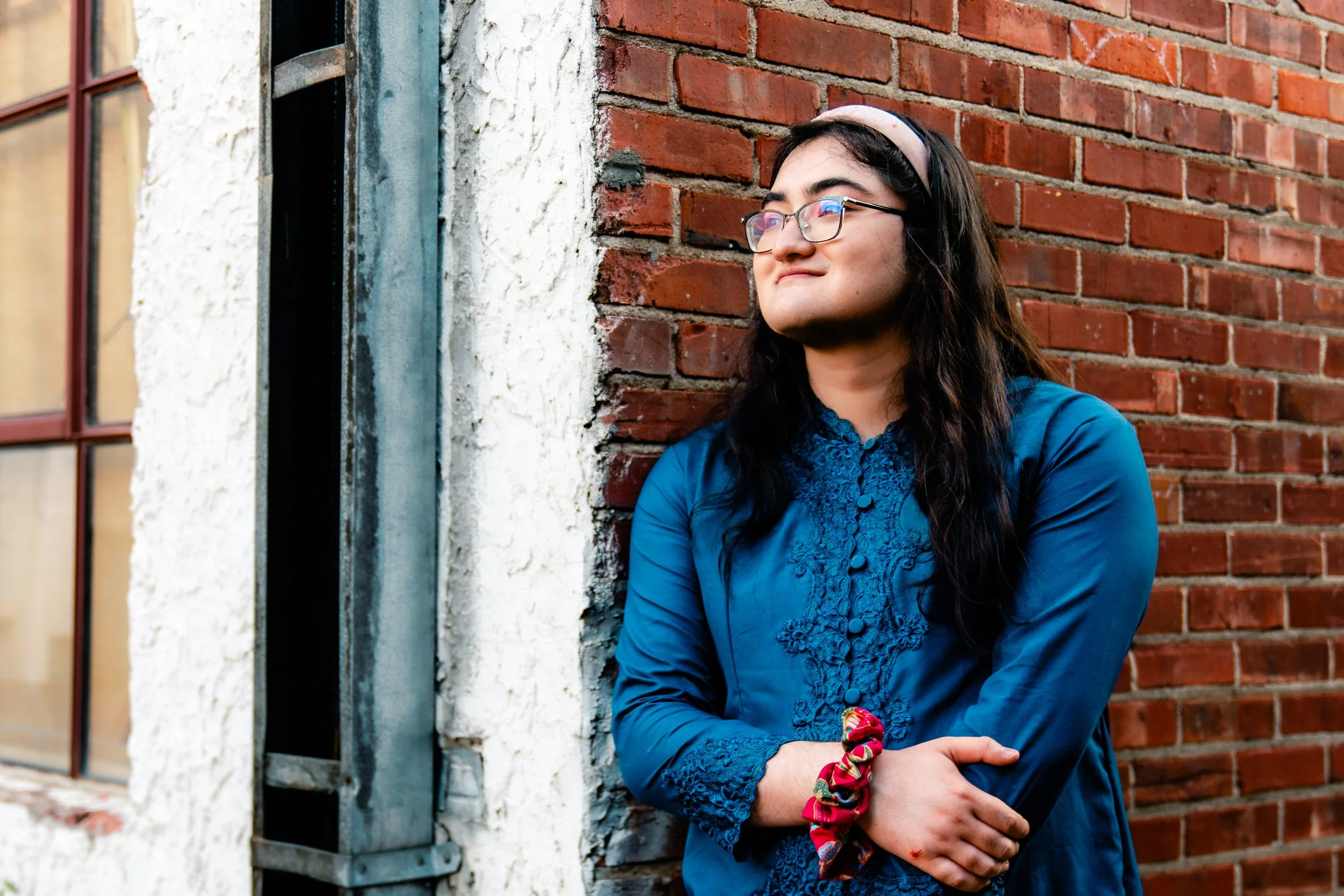 Eden smiles and leans against a brick wall.