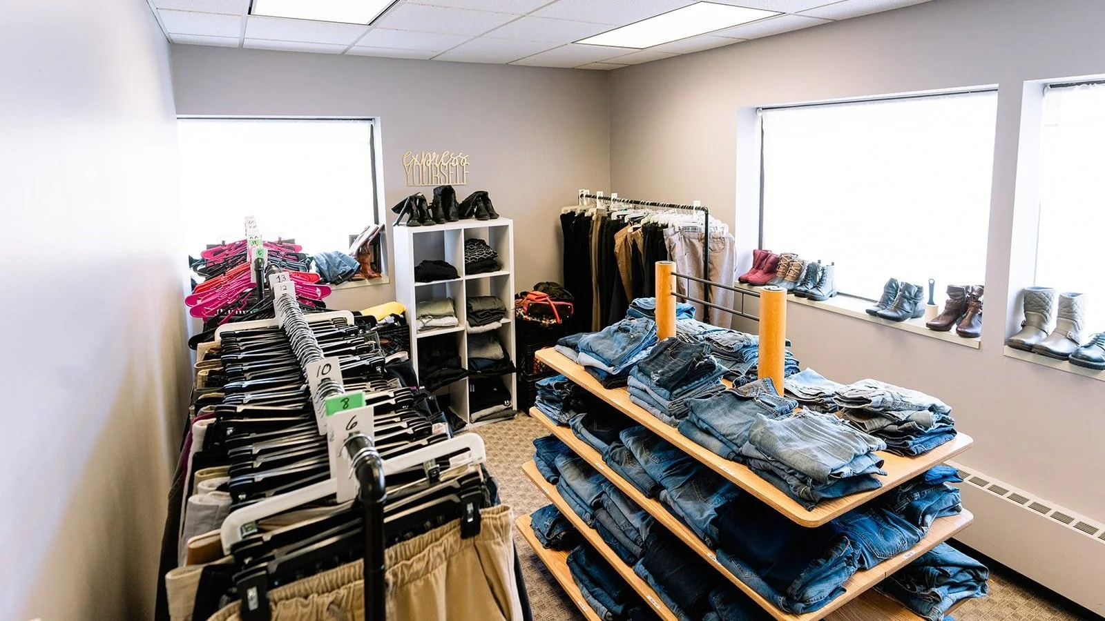 A room with racks and shelves of pants and shoes.