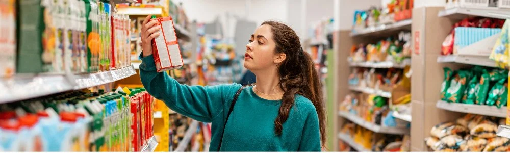 woman standing in store looking at nutrition label on box