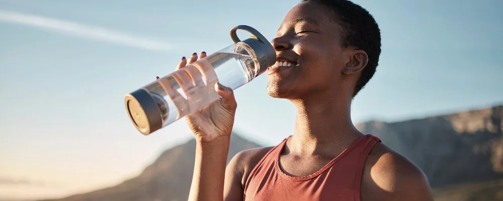 woman drinking out of a water bottle in the sun