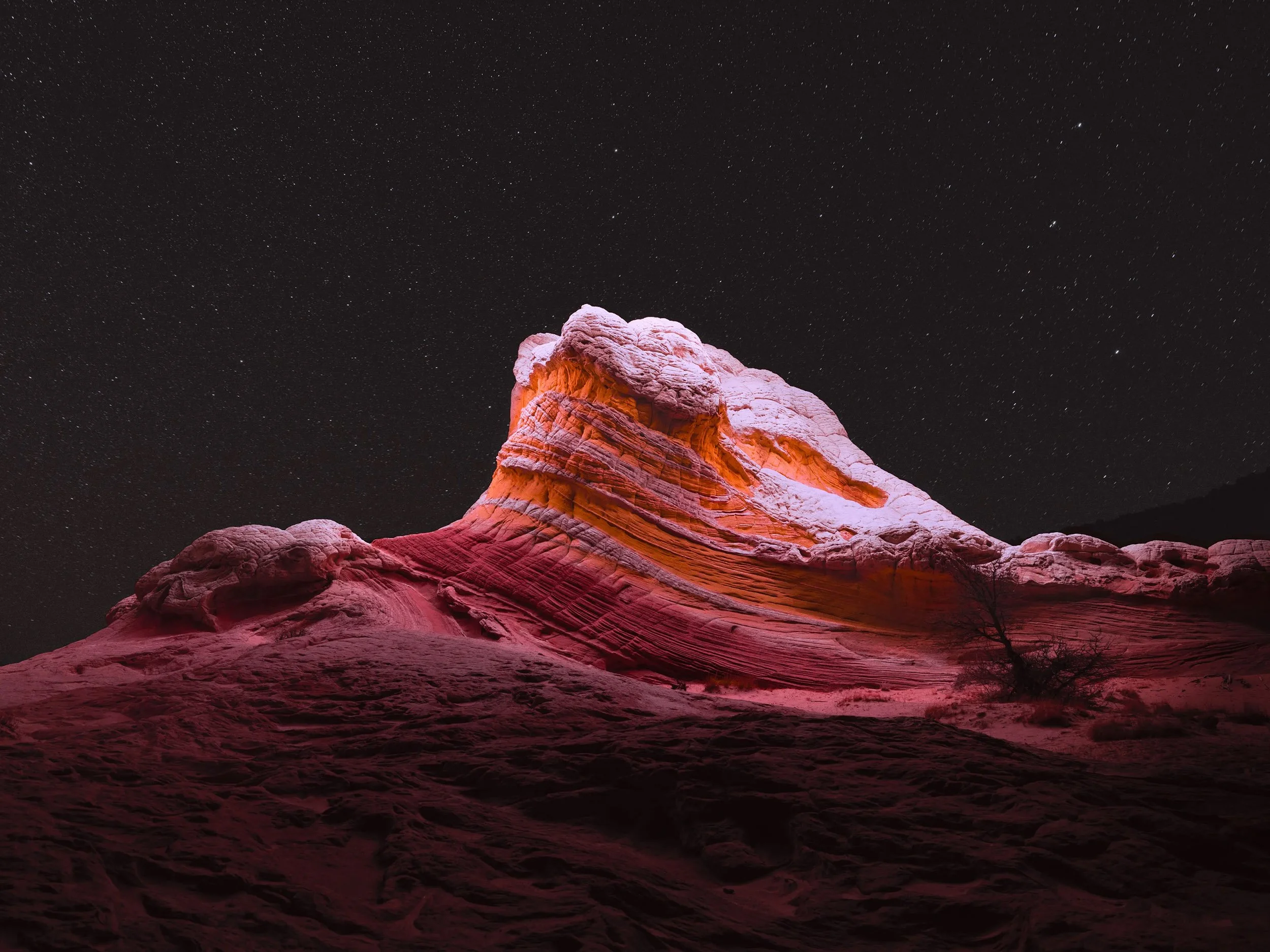 Nighttime desert landscape by Reuben Wu with illuminated stone forms beneath a dark sky.