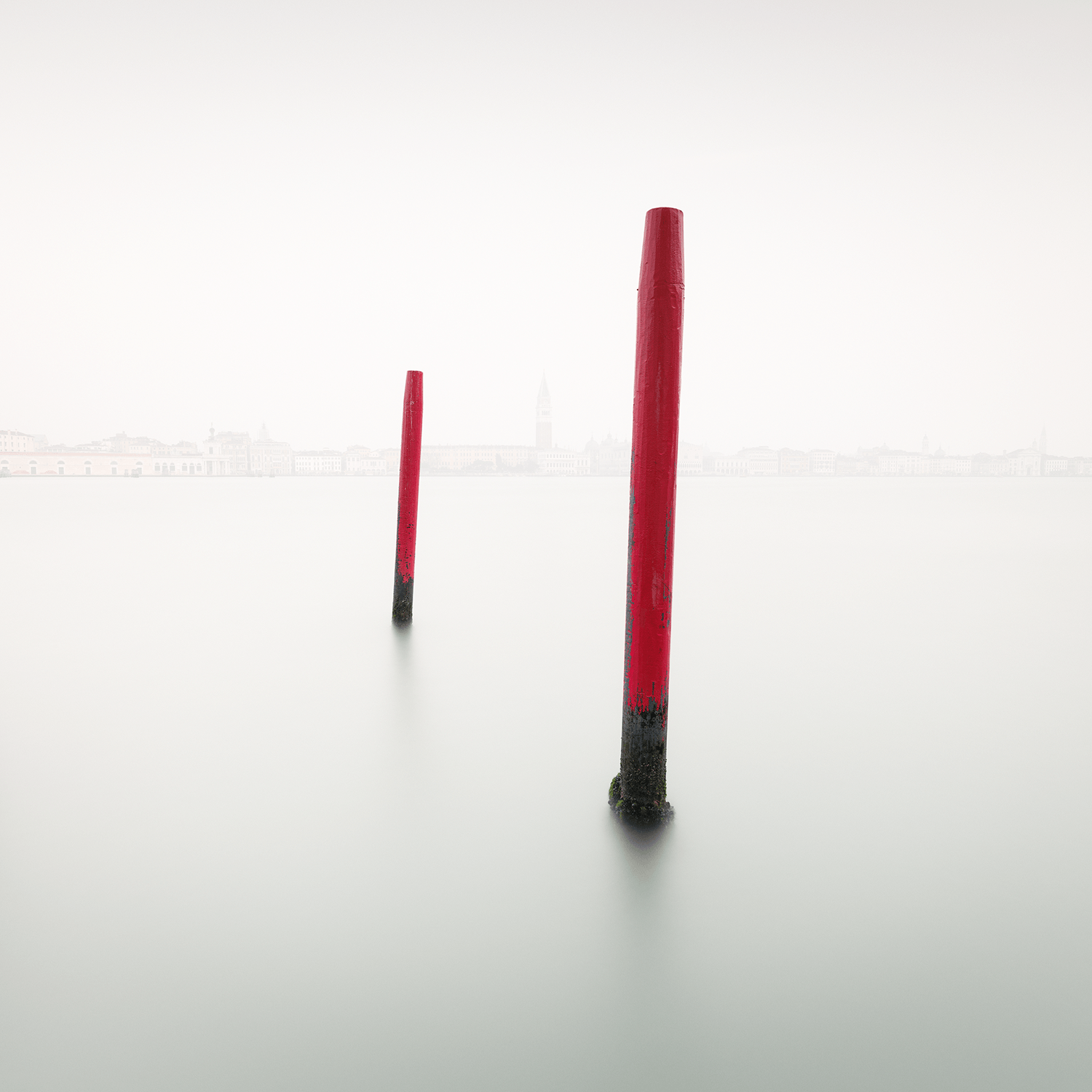 Two red poles stand out in smooth Grand Canal waters in Venice.