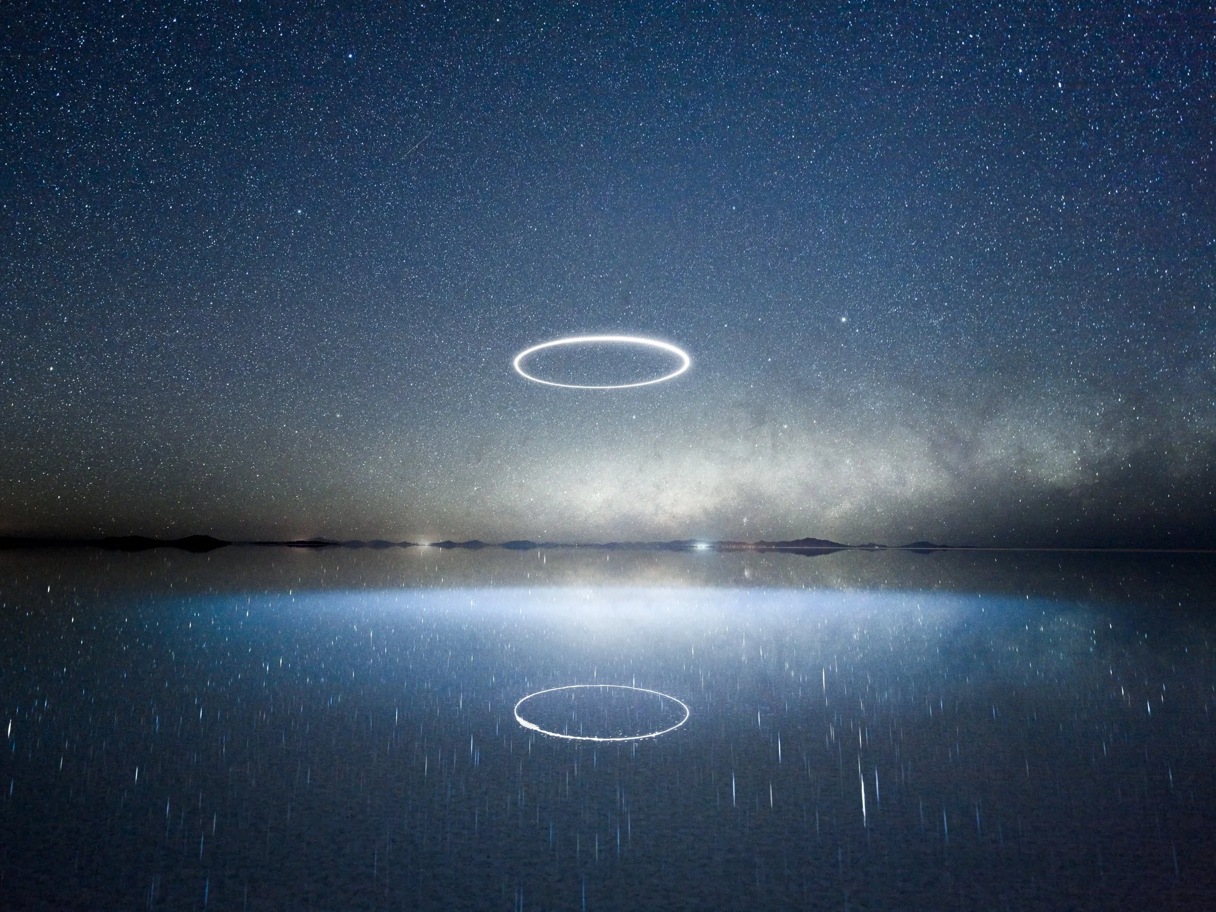 Night landscape photograph by Reuben Wu featuring an illuminated circle of light reflected in water below.