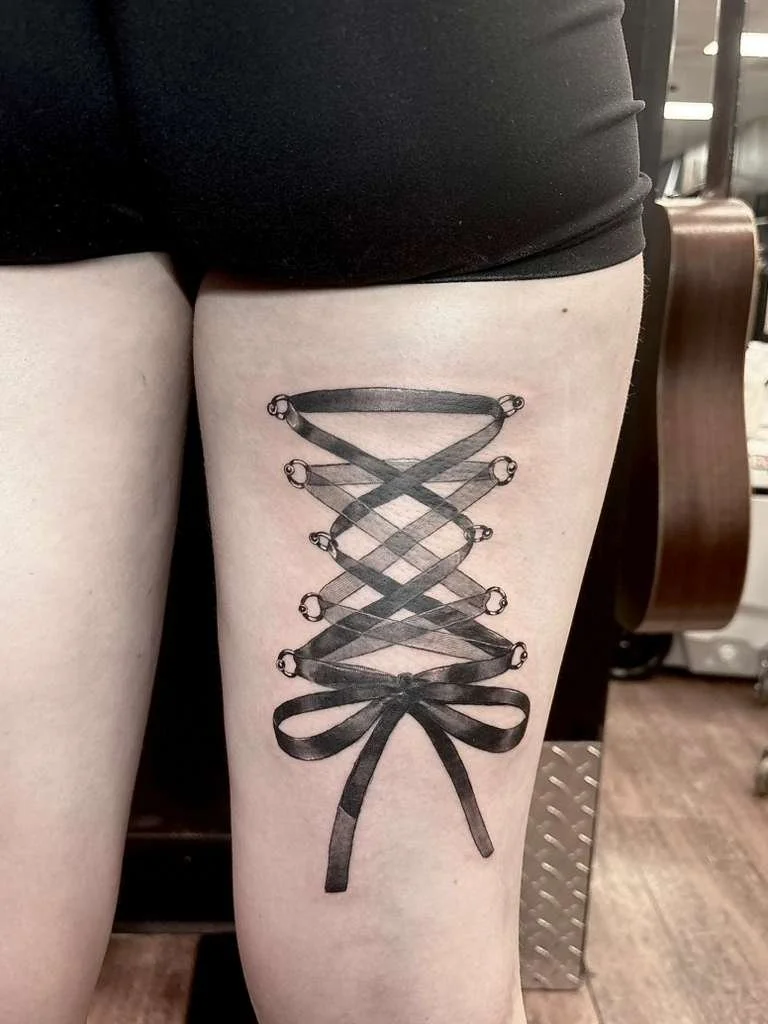 Close-up of a person's arm with a black and gray tattoo featuring butterflies, circular designs, and abstract patterns.