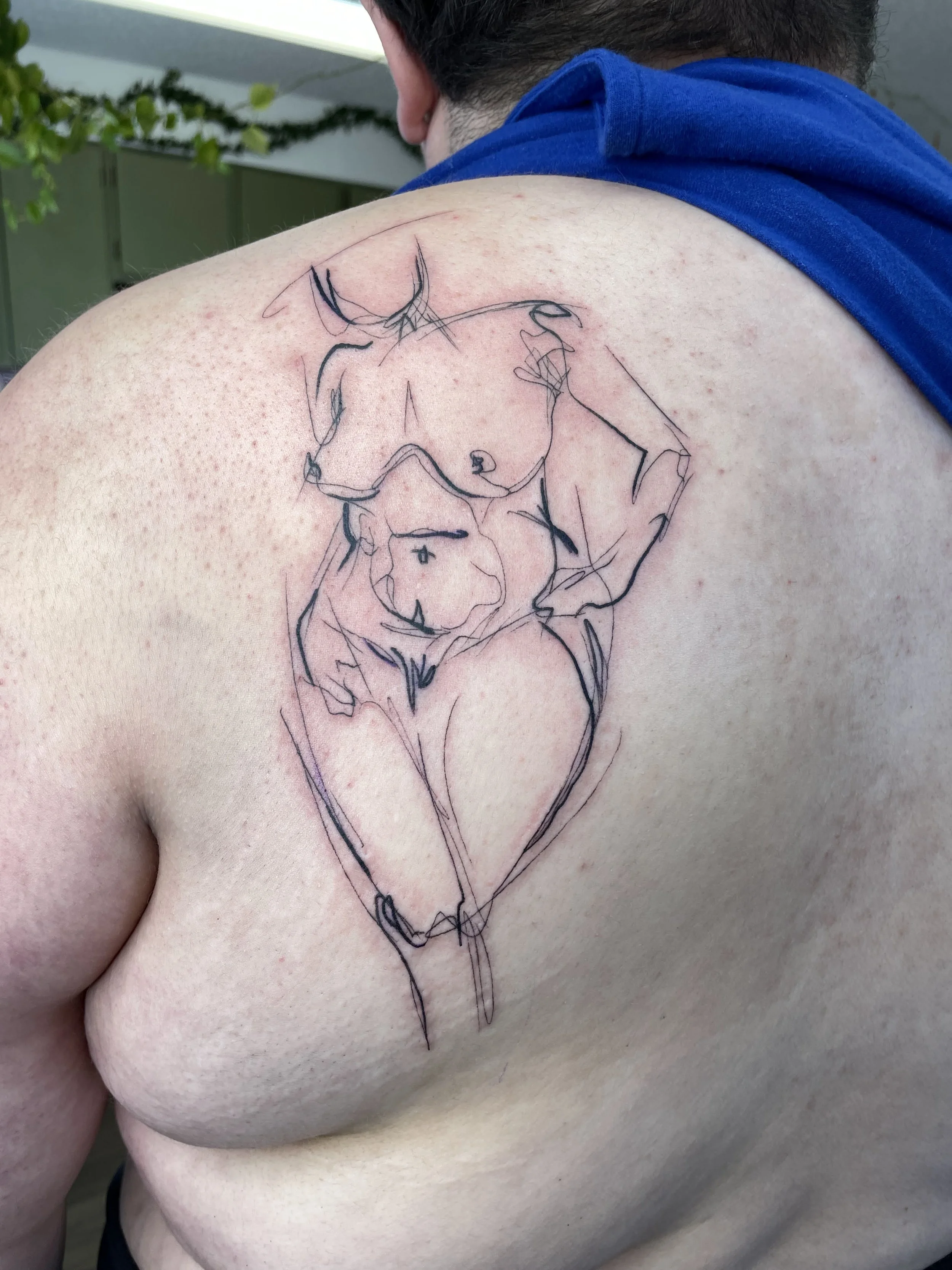 A person with a tattoo of a deer on their shoulder and upper arm, drawn in a minimalist, continuous line art style.