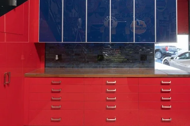 Red and blue custom commercial cabinetry with drawers, upper storage, and a work surface