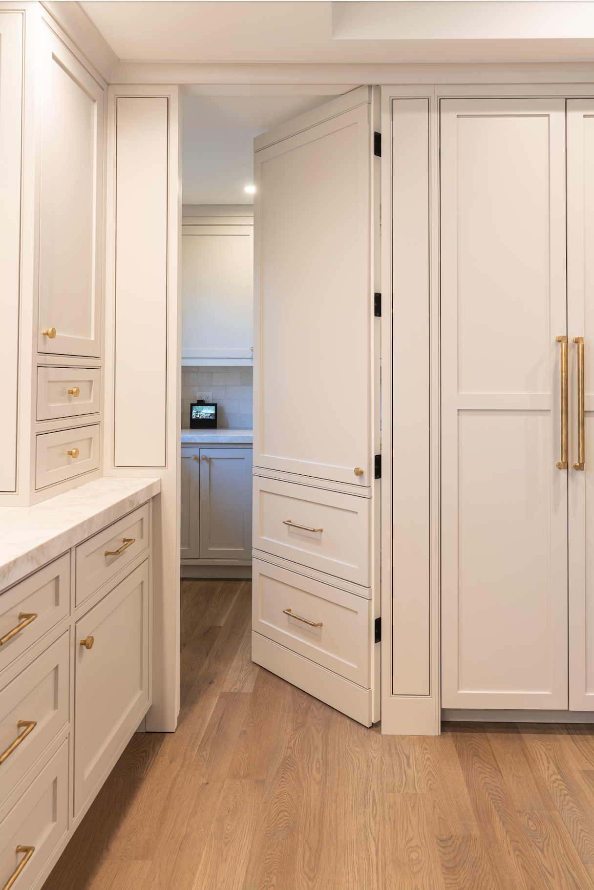 Floor-to-ceiling white custom cabinetry with integrated drawers and tall storage