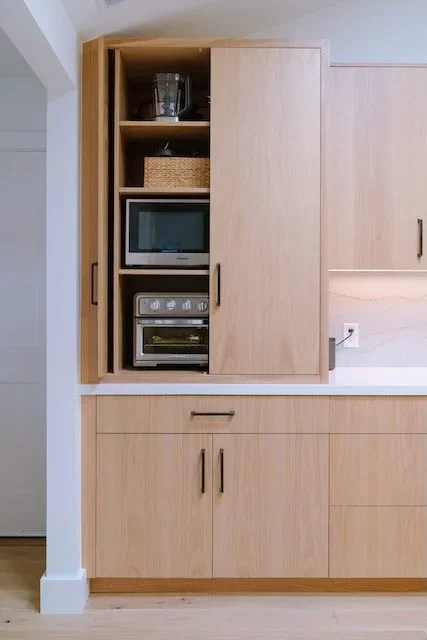 Custom light wood cabinetry with integrated shelves for countertop appliances
