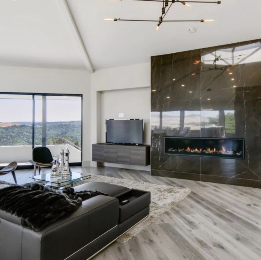 Modern Bay Area living room with custom floating media cabinetry, floor-to-ceiling stone fireplace, and expansive windows