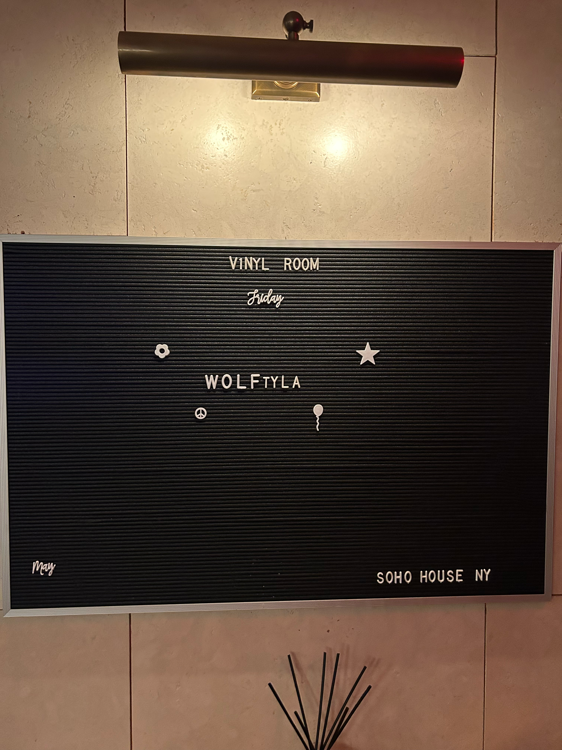 Signboard with text "VINYL ROOM Friday WOLF FLYLA SOHO HOUSE NY" on black background with decorative symbols.