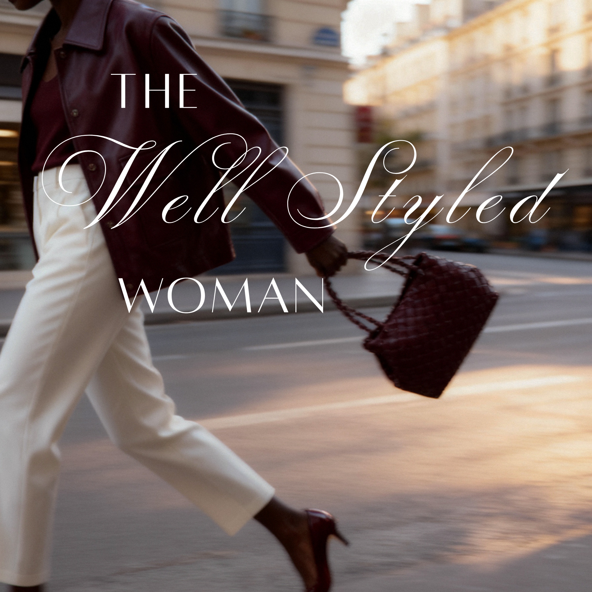 Person walking outdoors at sunset, wearing beige pants, a burgundy leather jacket, and carrying a red quilted handbag.