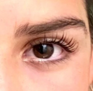 Close-up of a person's eye with long eyelashes and a defined eyebrow.