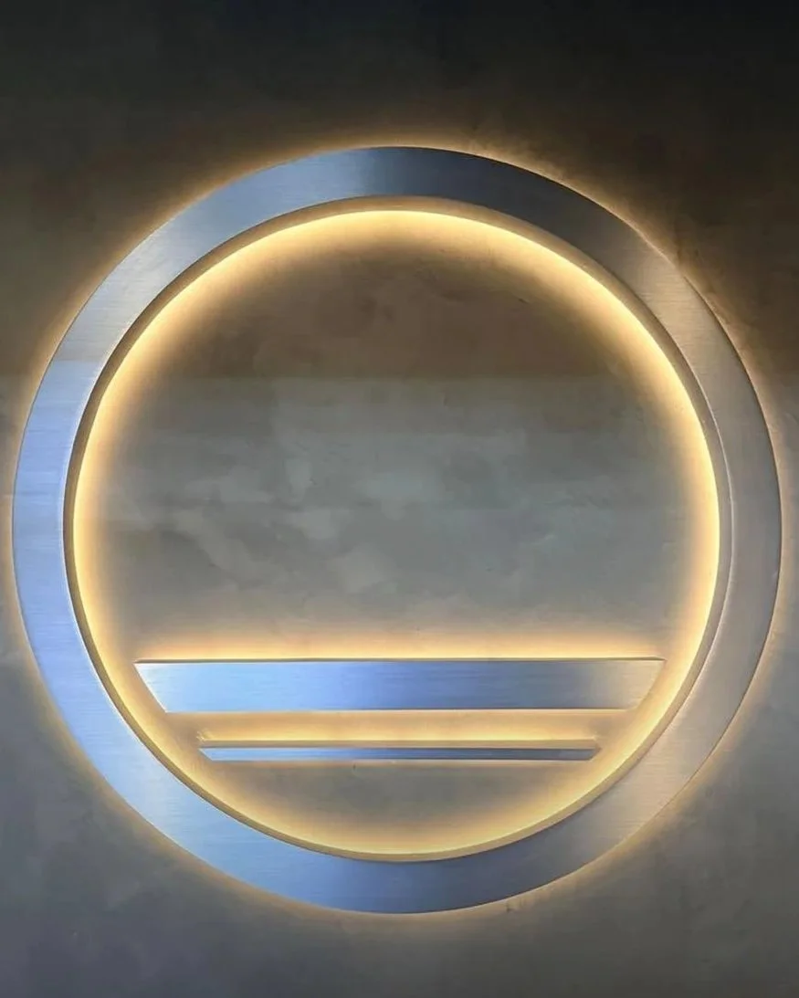 A circular light fixture with glow inside, featuring three horizontal bars at the bottom section, mounted on a wall.