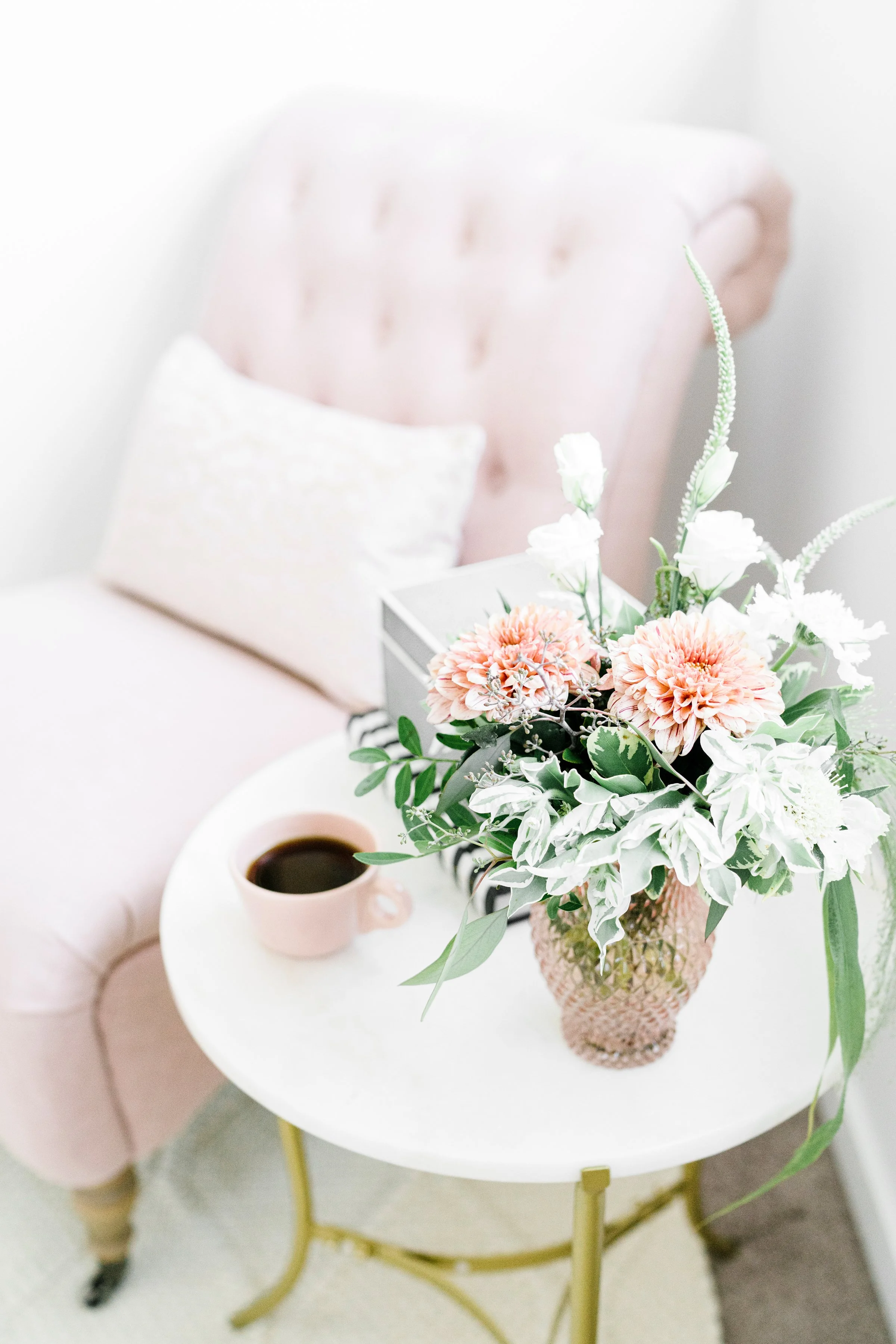 Beautiful pink client chair in therapists office with flowers and cup and coffee on side table
