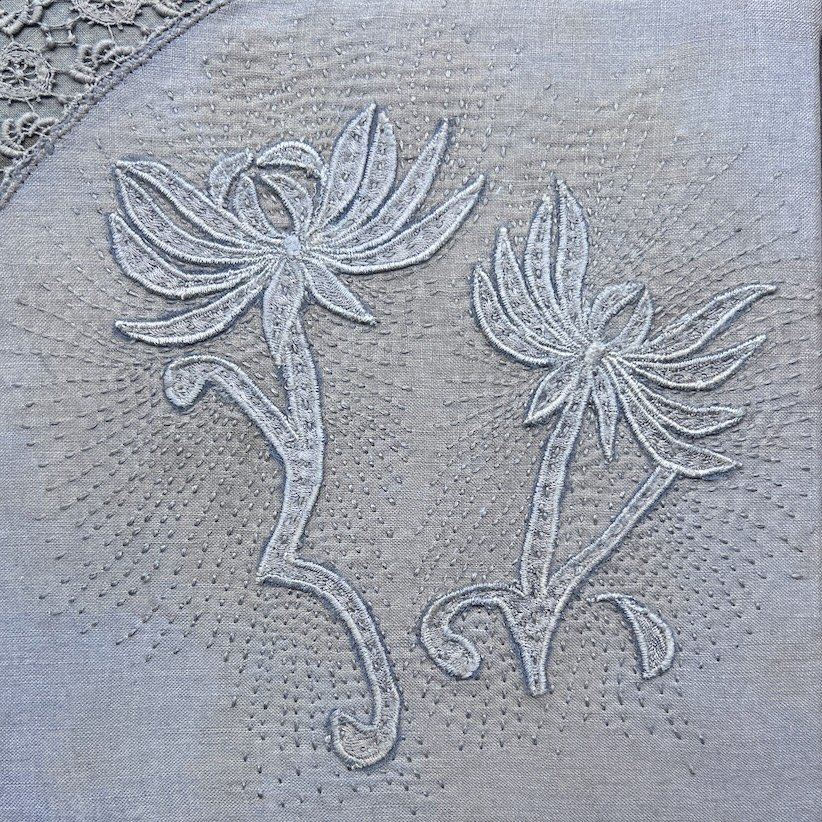 Enduring Trace 2026 
Hand-dyed silk lace fragments from a vintage lace collar appliquéd on hand-dyed vintage serviette with hand stitching.
Two lace blooms rest on a well-used domestic cloth, suggesting companionship and shared resilience. Stitching 