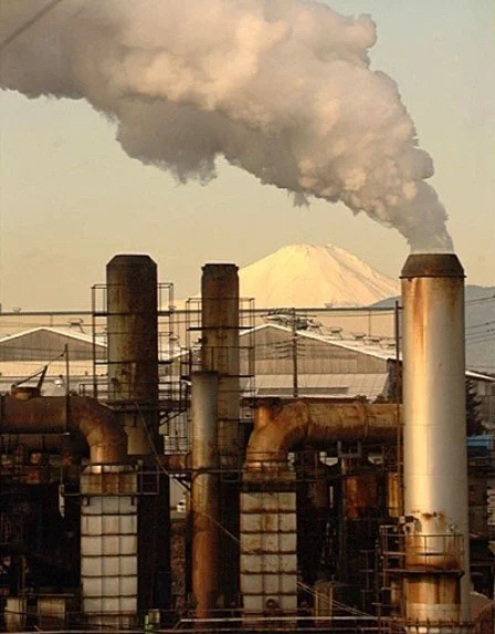 An incinerator emitting white, opaque smoke with Mt. Fuji in the background.