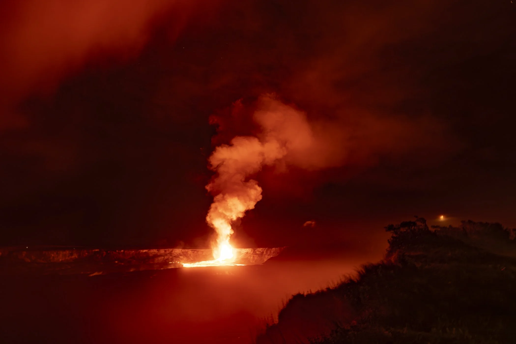Nighttime volcanic eruption with lava and ash plume.