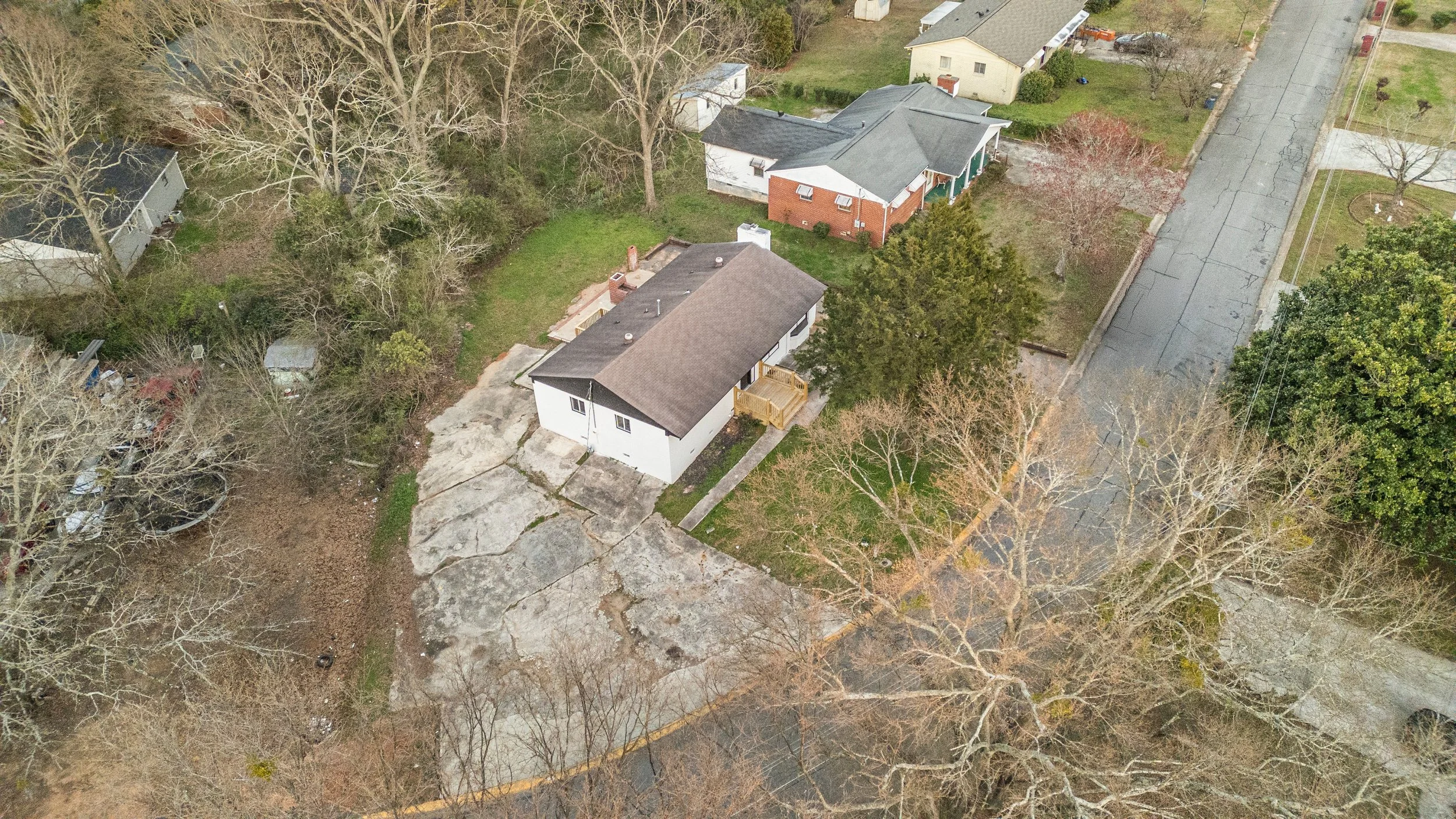 Aerial view of a backyard and neighboring houses in Athens, GA with trees and a paved road.