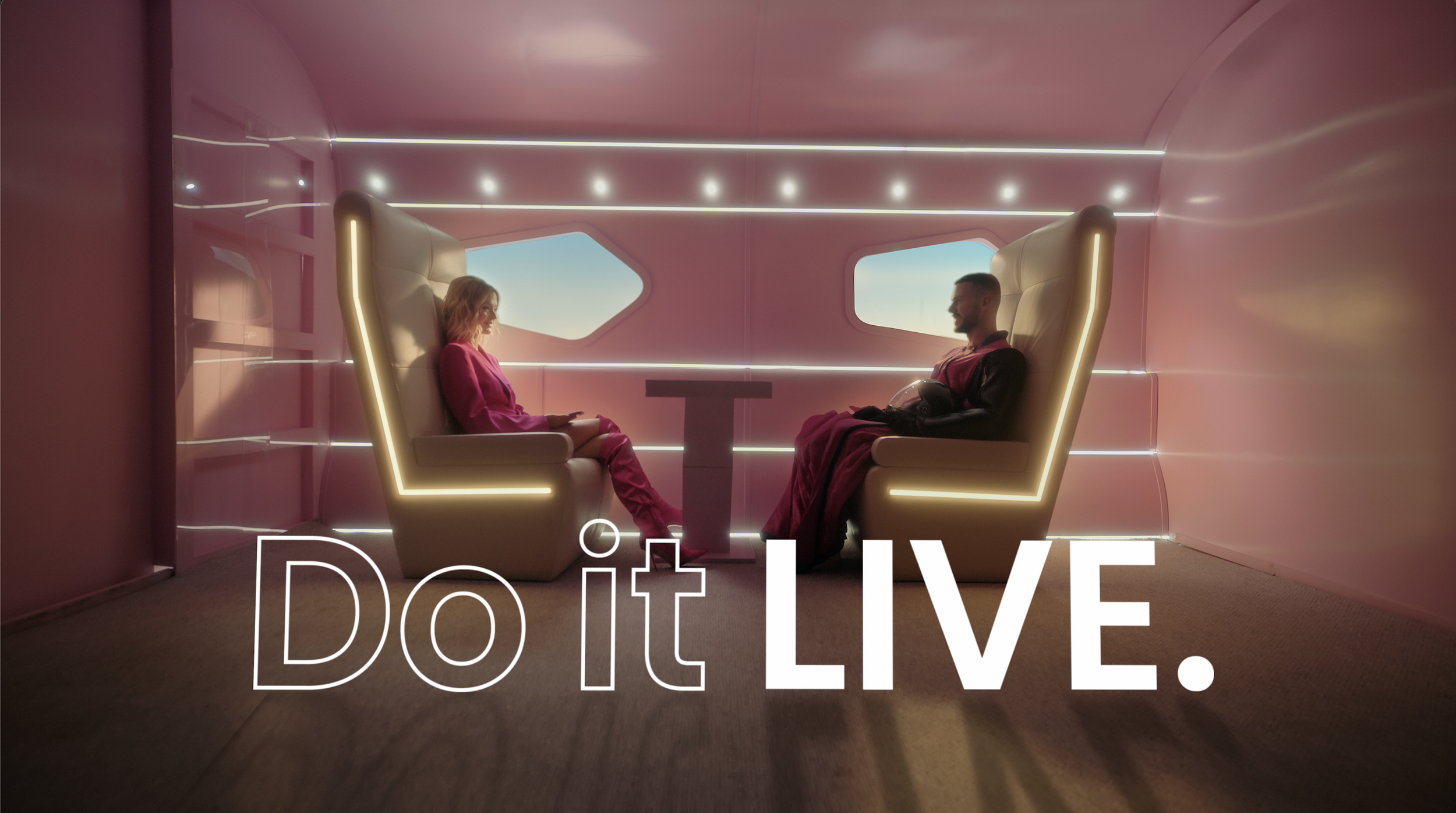 Still from the Do it LIVE. launch film: two people in pink lounge seats facing each other.