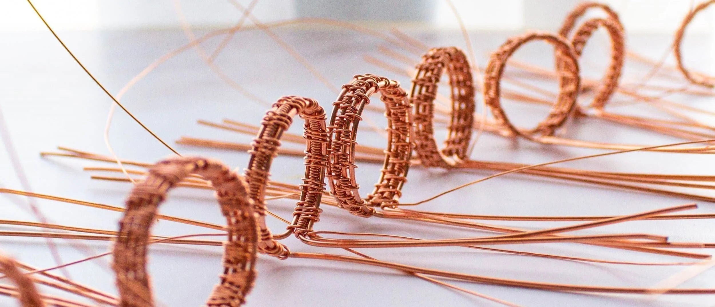 Wire wrapped copper wire bands arranged on a white flat surface.
