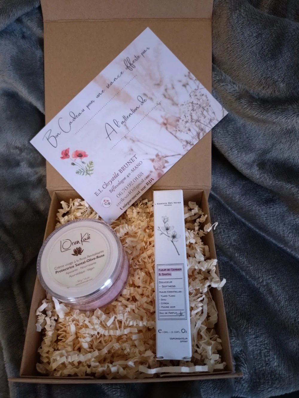 Un coffret cadeau contenant une crème visage, un parfum aux huiles essentielles, et un bon pour une séance de réflexologie.