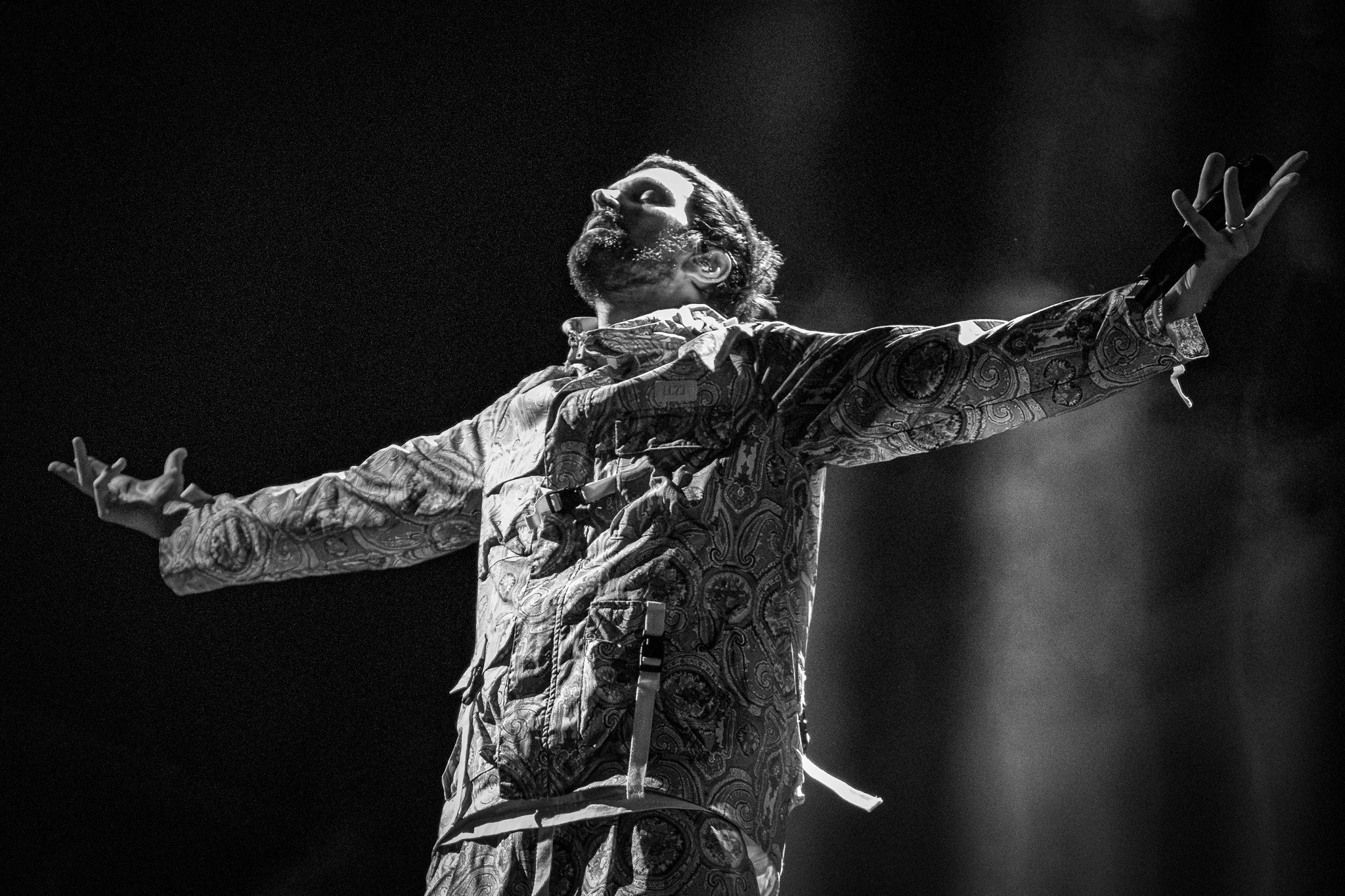 Serge Pizzorno stands arms outstretched  against a back drop while playing live with Kasabian at Truck Fest Festival 2025
