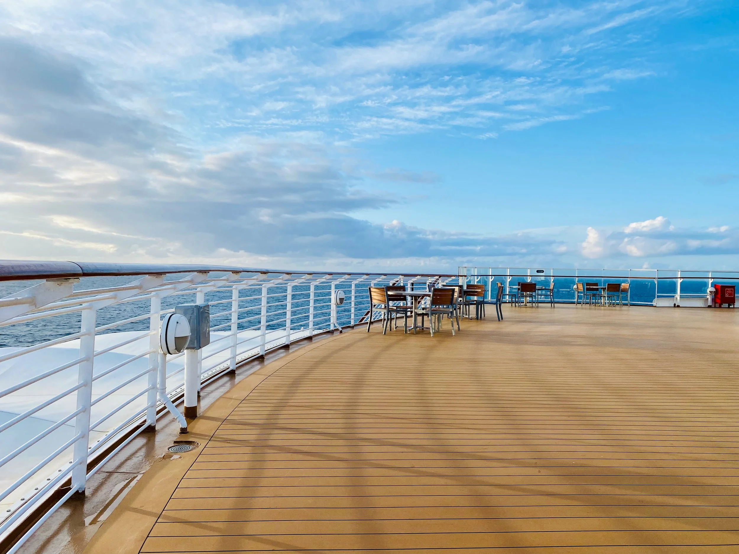 picture of the deck of a Disney ship, looking out to sea with a beautiful sky and few clouds.