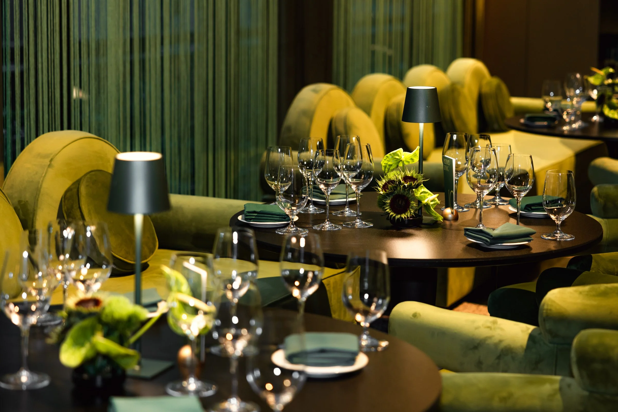 Table settings in different shades of green at The Department at Hudson's for a culinary event.
