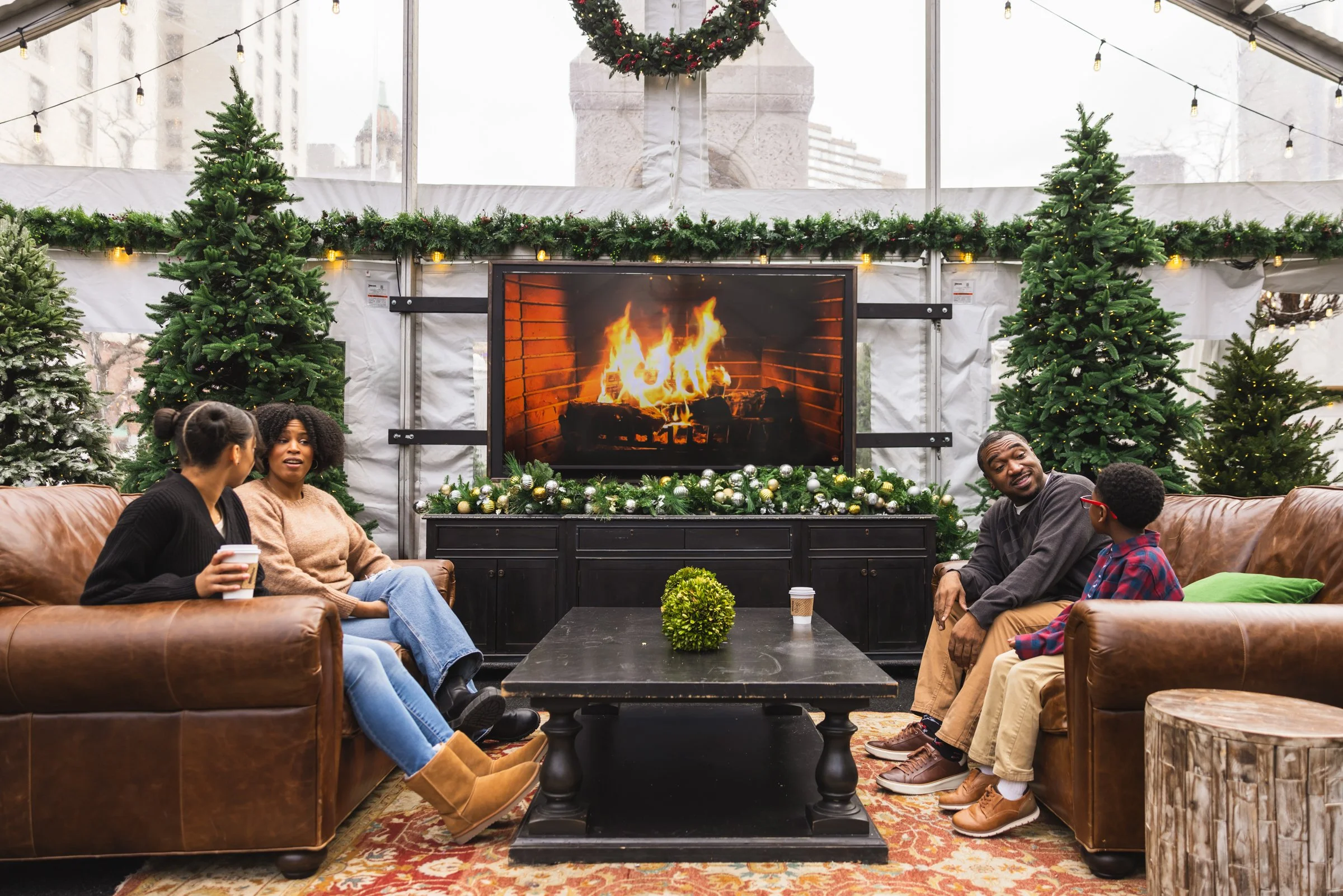 Interior photo of the Cadillac Lodge at Cadillac Square in downtown Detroit, featuring a group sitting in front of a digital fireplace.