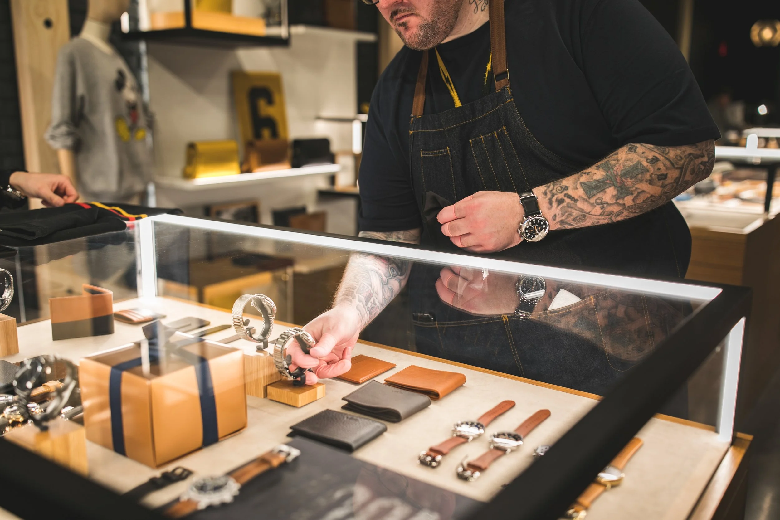 Interior photo of Shinola Detroit featuring an employee selecting a watch from a display case.
