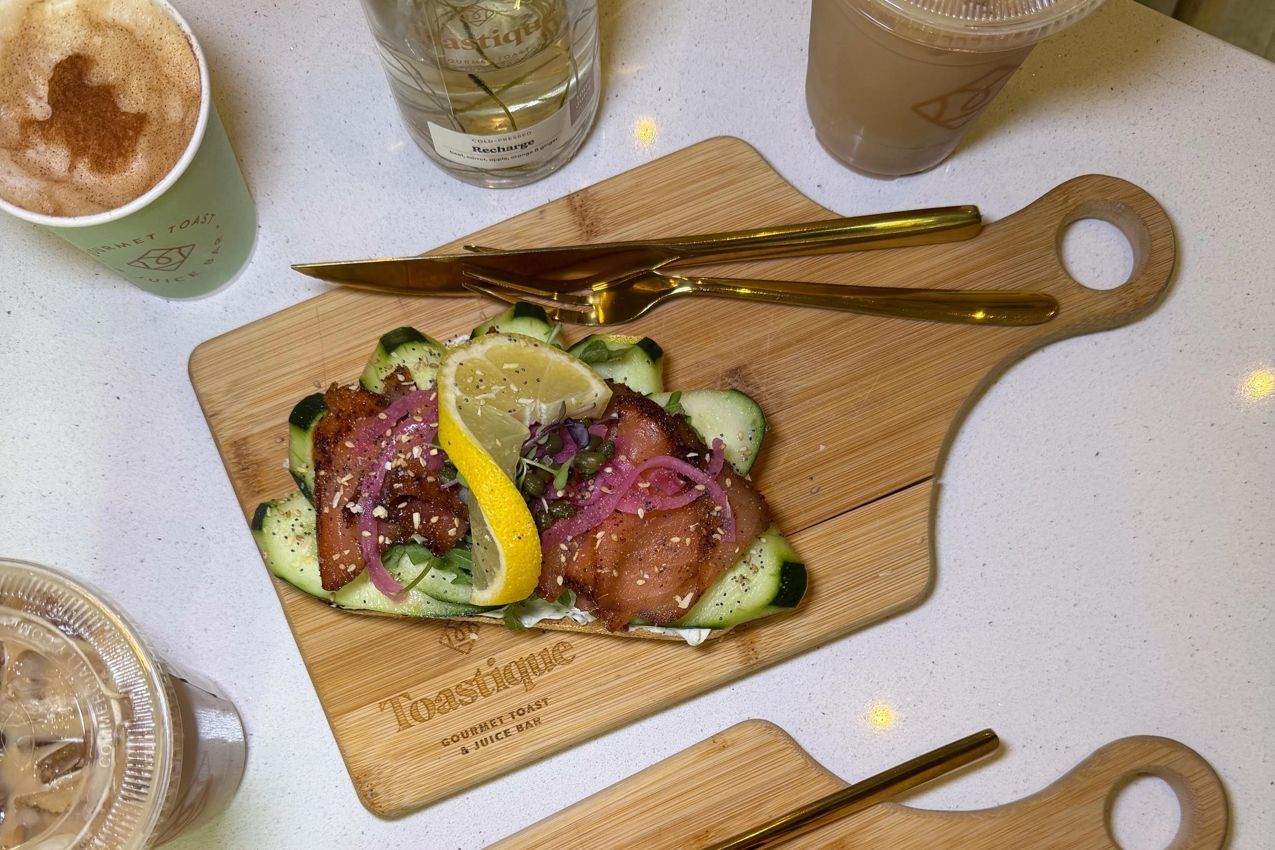 Product photo of a salmon and avocado toast on a cutting board from Toastique.