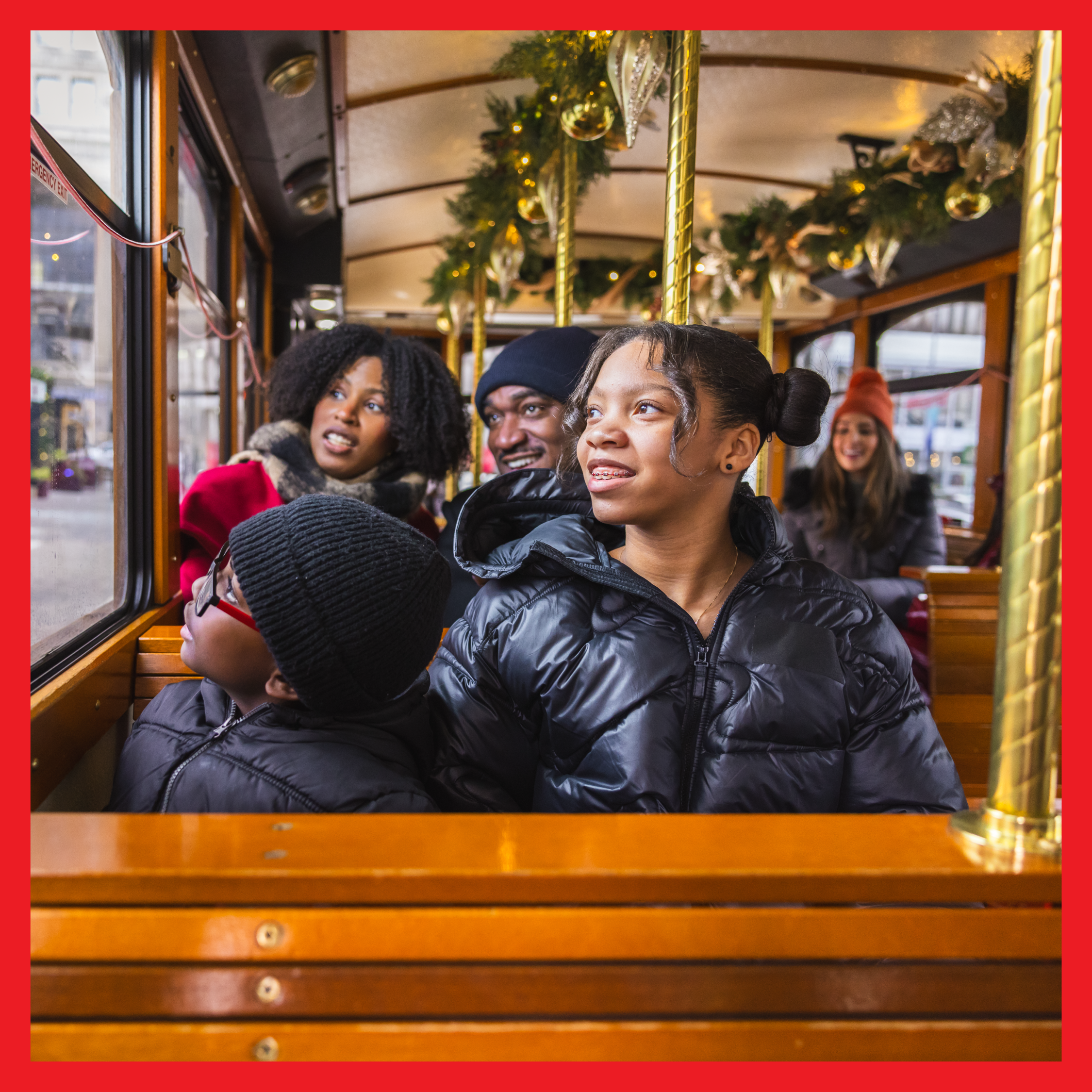 A family inside the Holly Trolley in downtown Detroit, looking out the window.