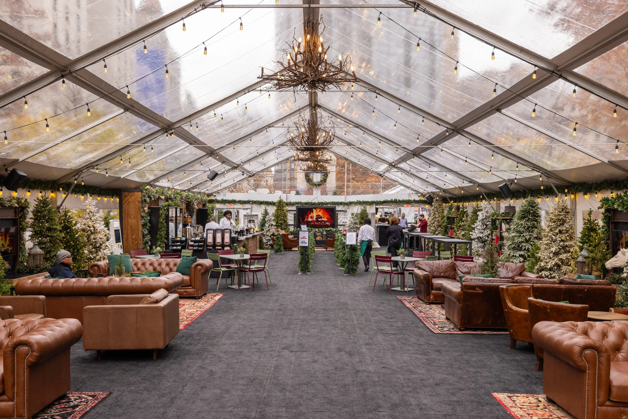 Interior photo of Cadillac Lodge at Cadillac Square, downtown Detroit, showcasing seating configurations and various holiday decorations like Christmas trees and lights.